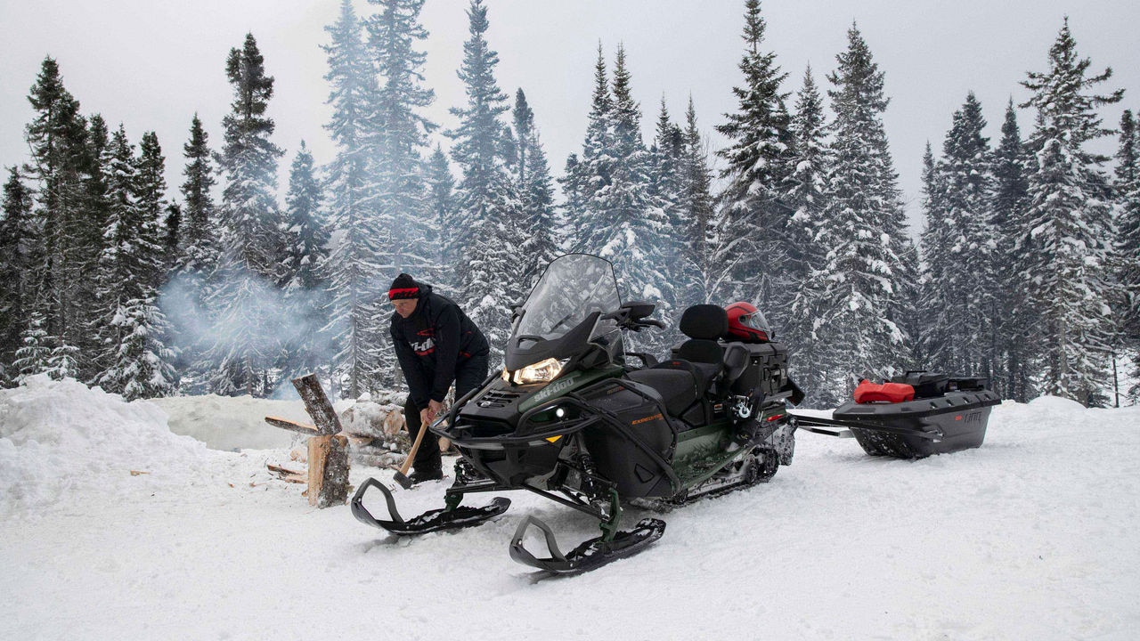 Muž pracuje vedľa jeho Ski-Doo Expedition