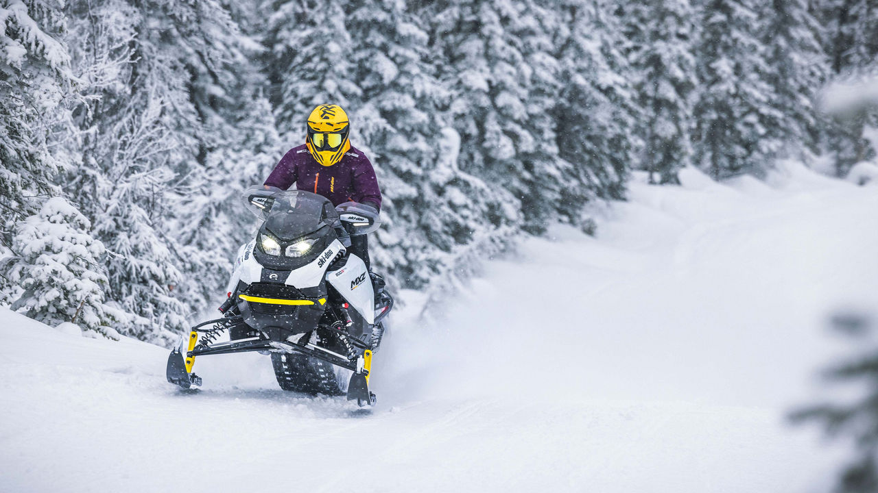 Woman riding the MXZ Adrenaline with Blizzard Package in trail