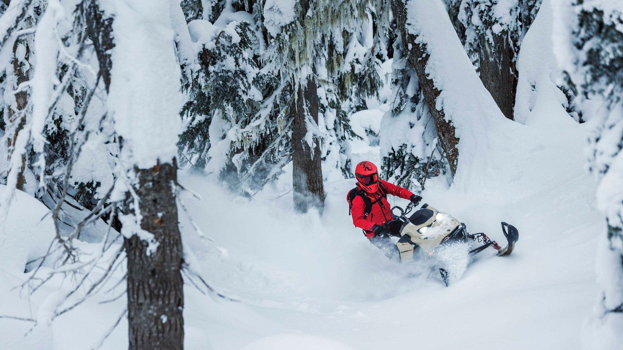 Žena jazdí na Ski-Doo Summit pomedzi stromy