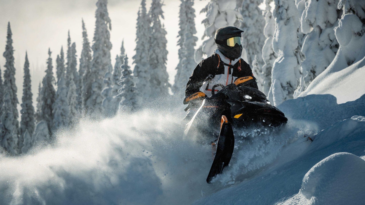 Man going up a hill with a Ski-Doo Summit