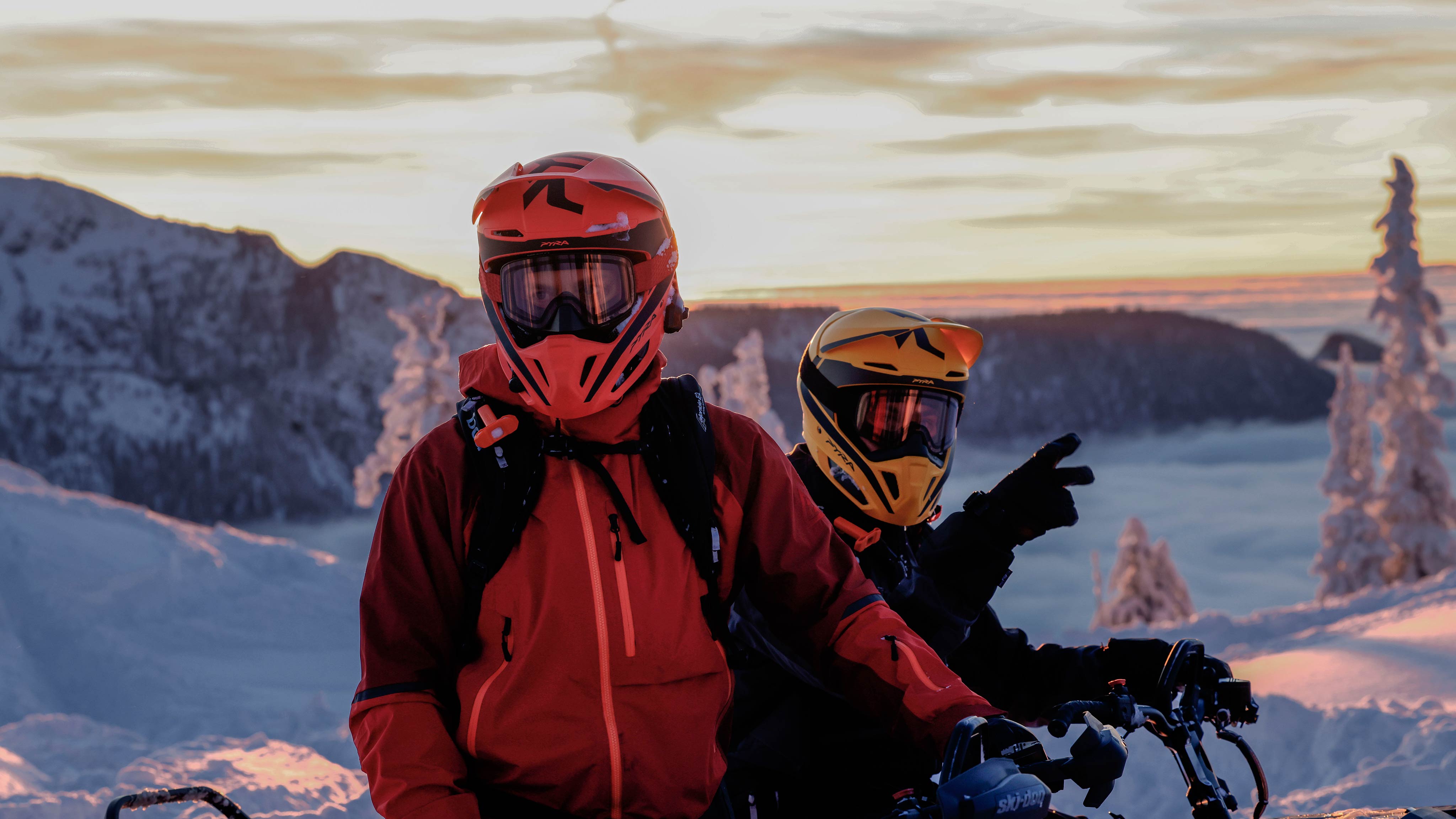Two snowmobile riders wearing Pyra helmets