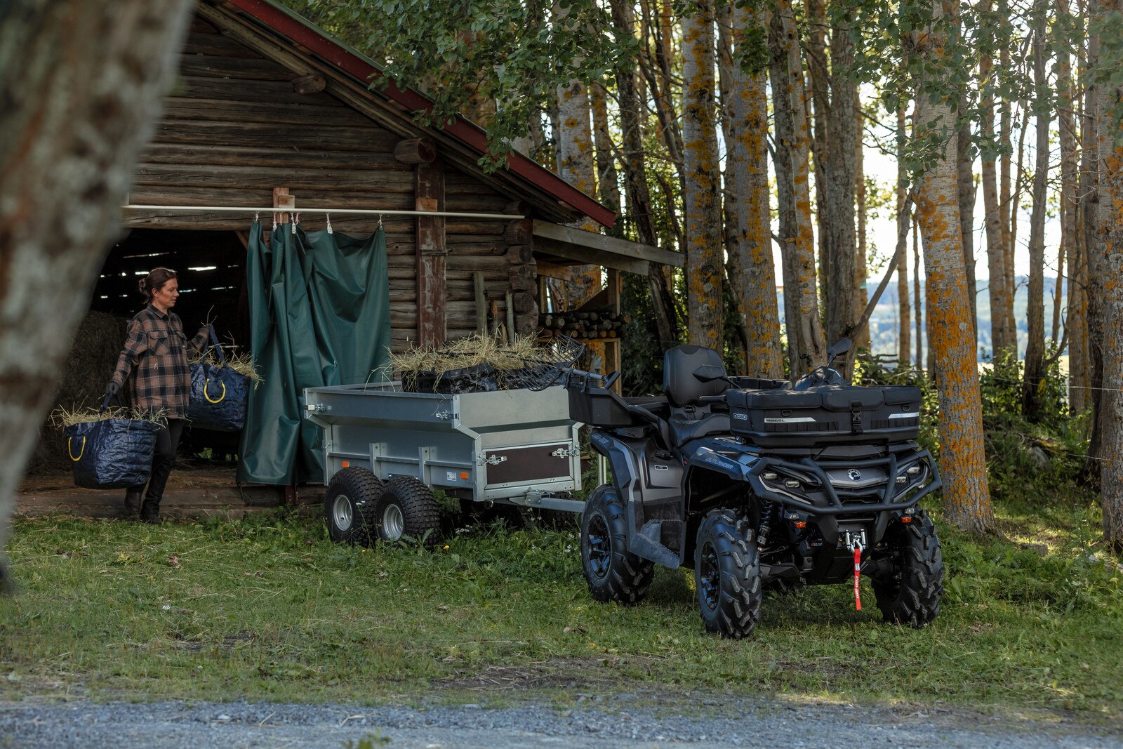 A woman loads hay into a trailer.