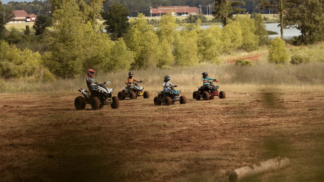 Cztery pojazdy Can-Am ATV między drzewami