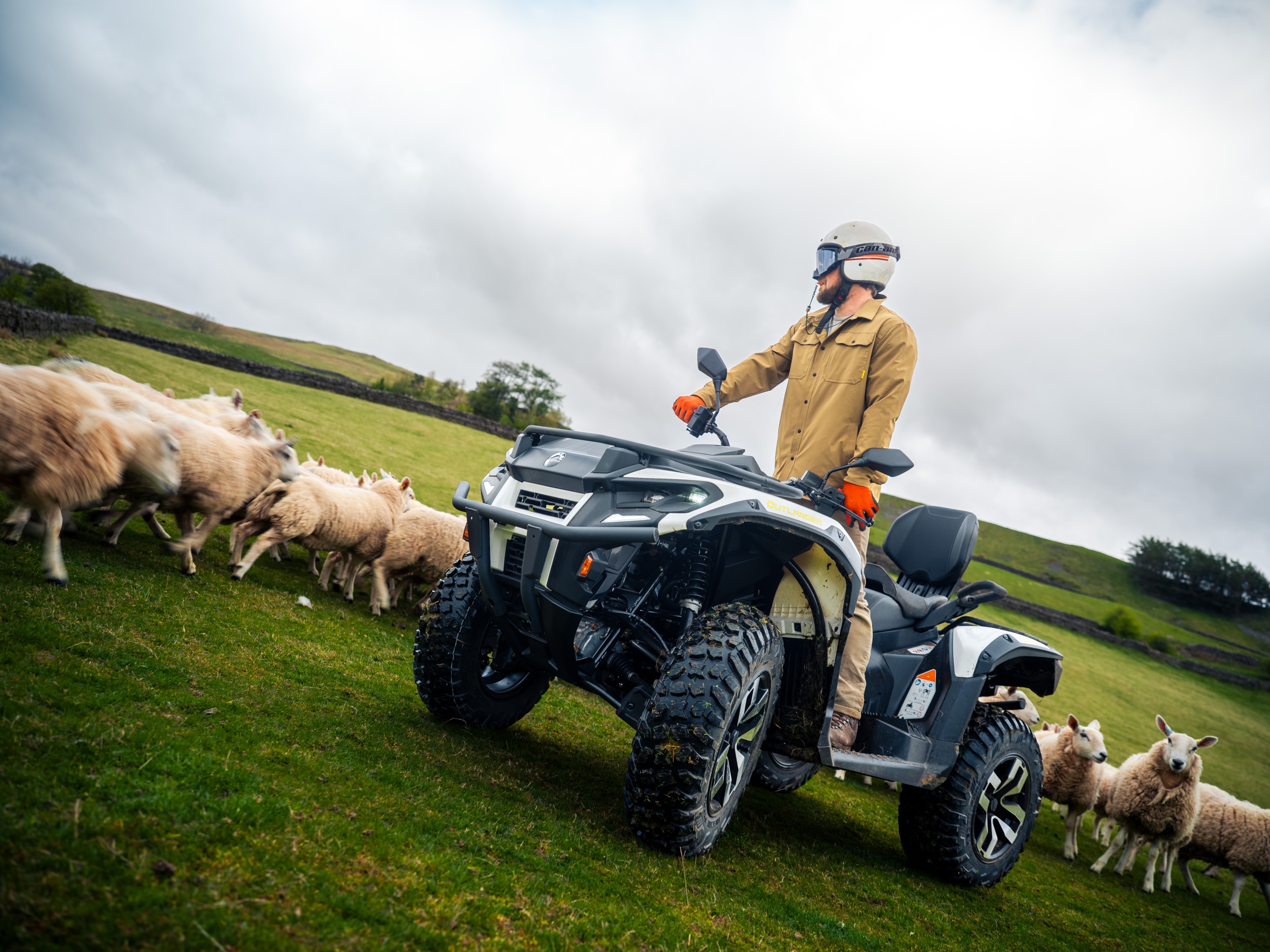 Farmer standing on a Can-Am Outlander MAX Electric ATV next to sheeps
