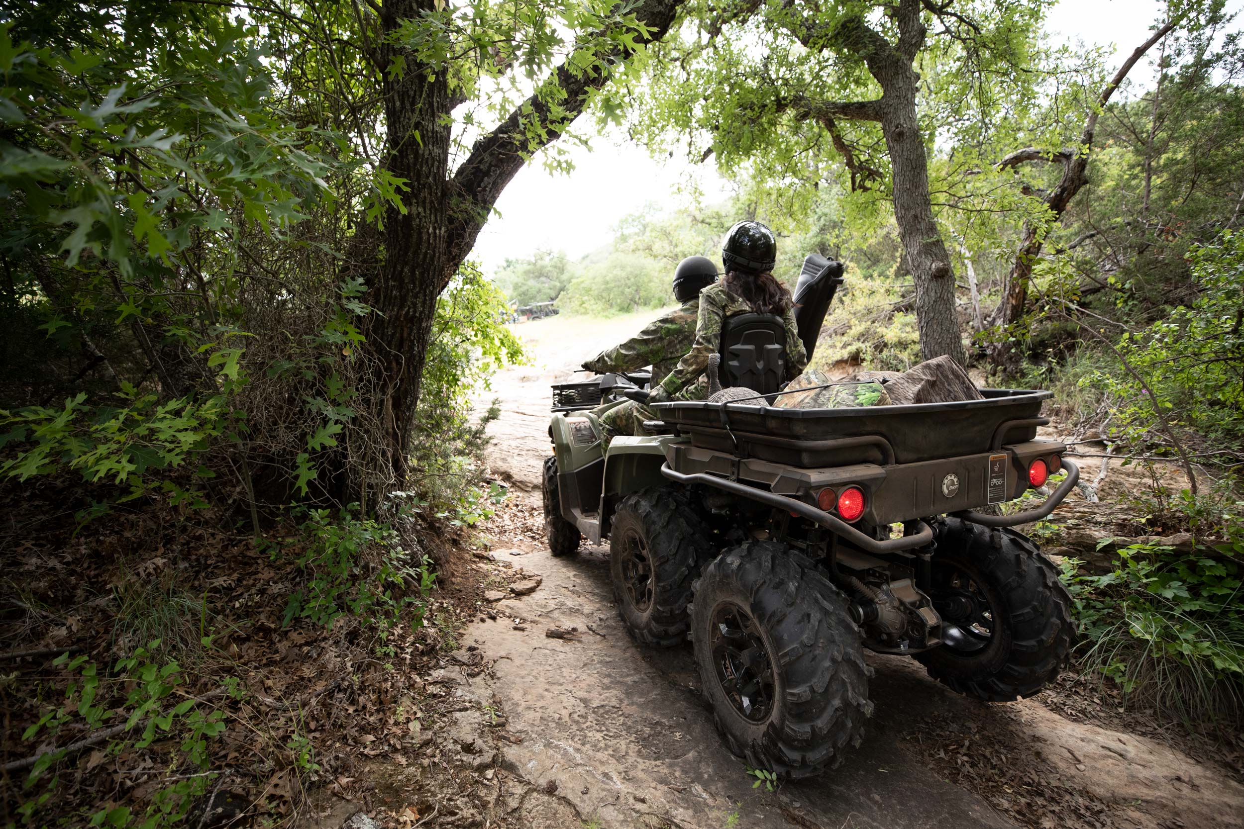 Two people on a 2-up Can-Am Outlander MAX 6x6 DPS ATV filled with hunting gear