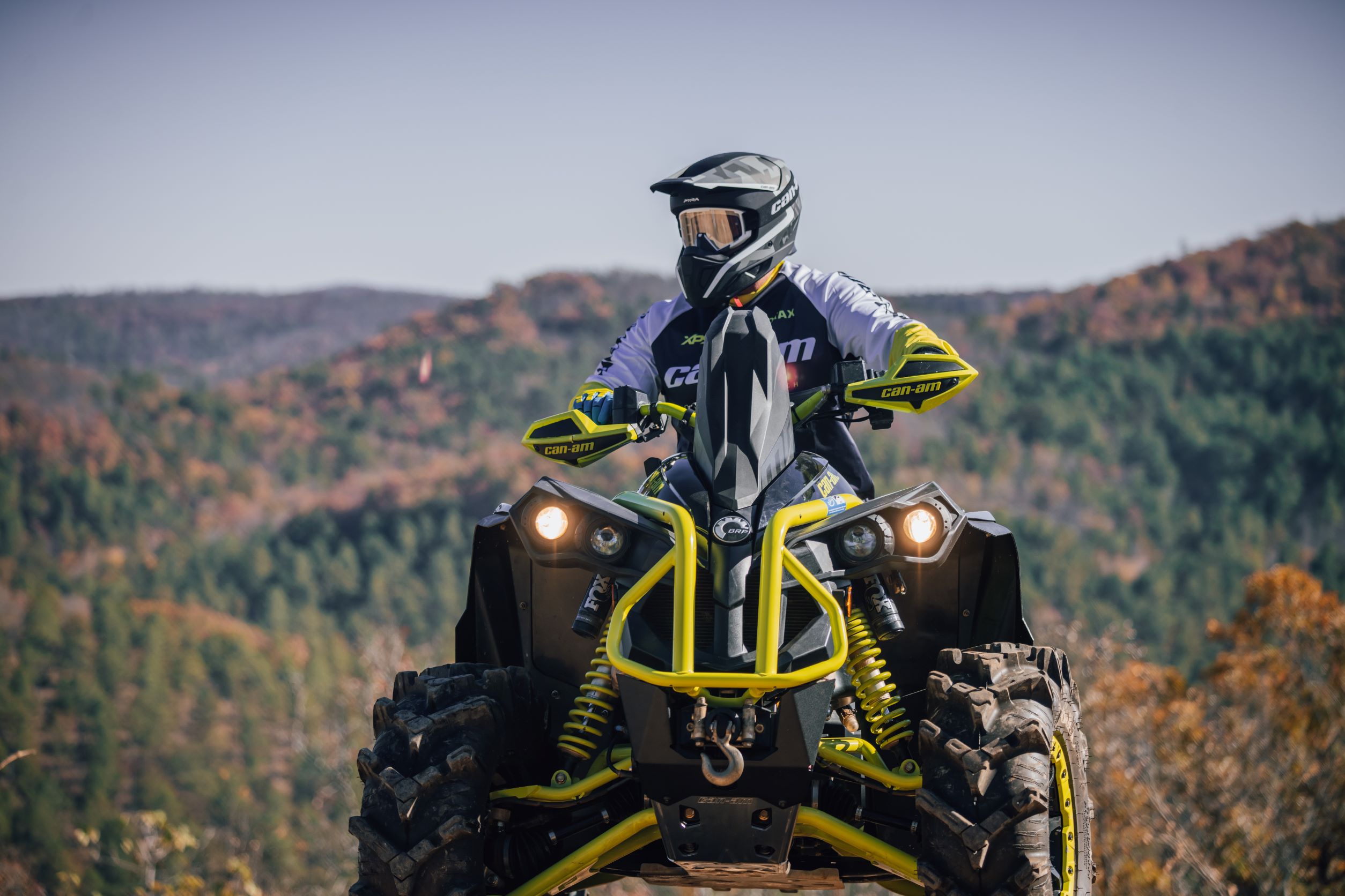 Front view of a Can-Am rider sitting on his parked Renegade enjoying a mountainous view.
