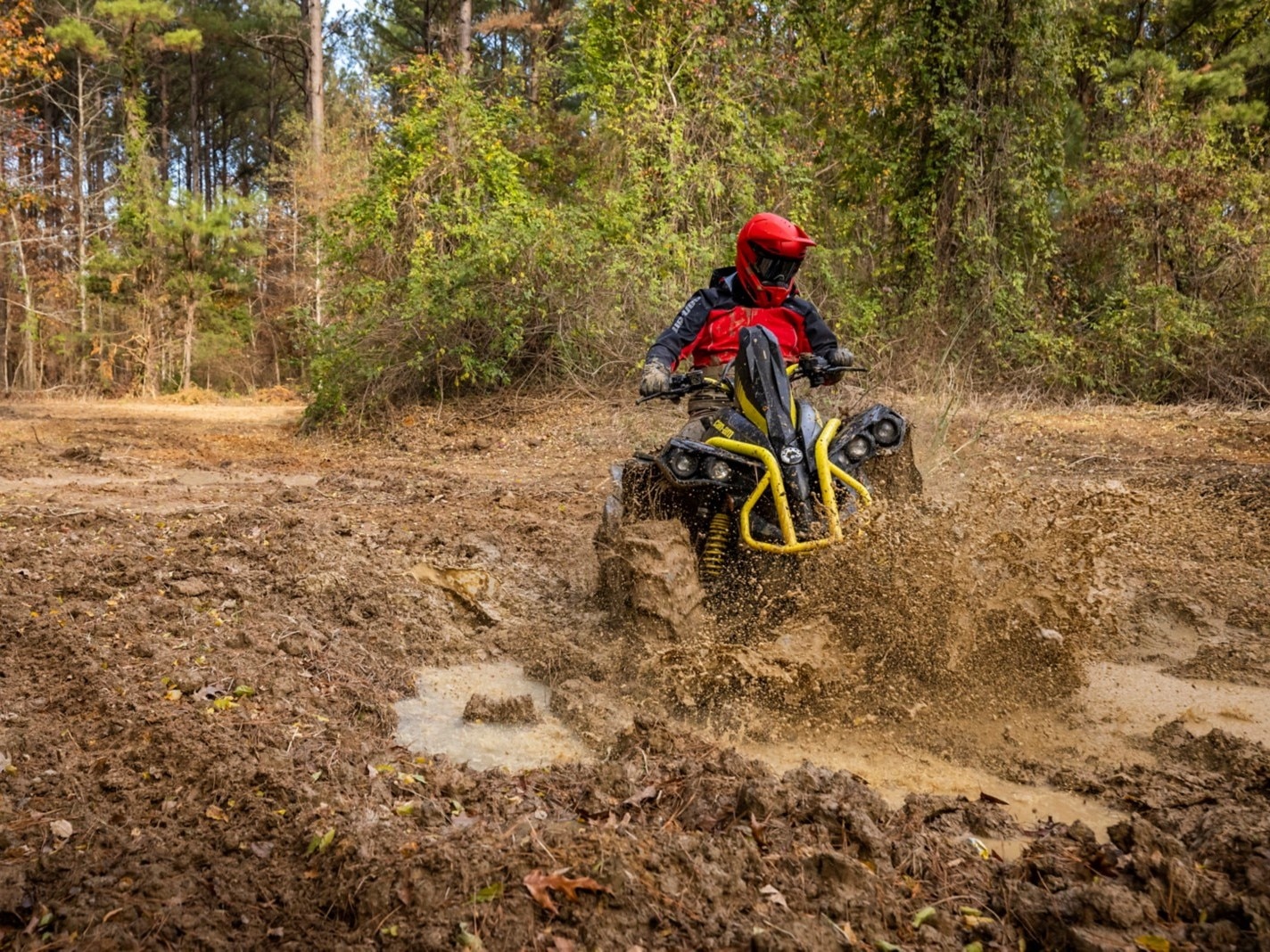 Osta Cruiser oblečený v terénnej výstroji Finntrail, ktorý sa rúti blatom na svojom žltom Can-Am Renegade X MR