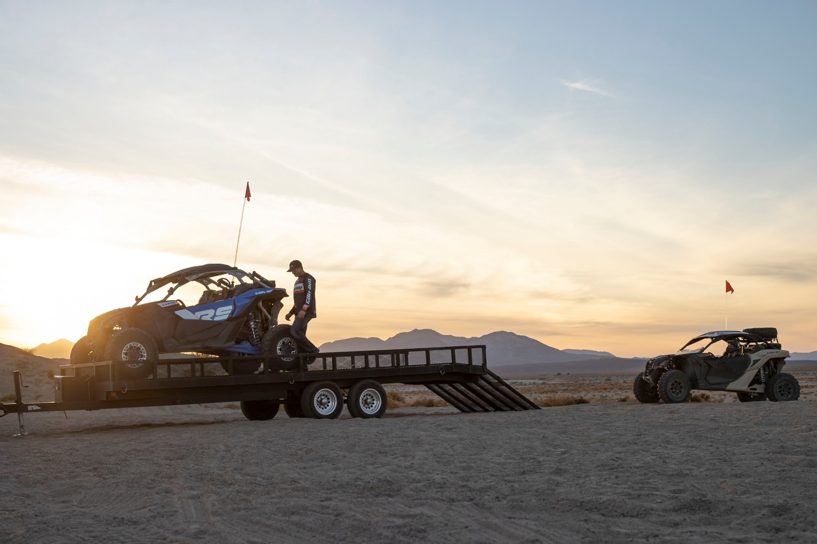 Two Can-Am riders loading their Maverick X3s on the trailer after a day of riding