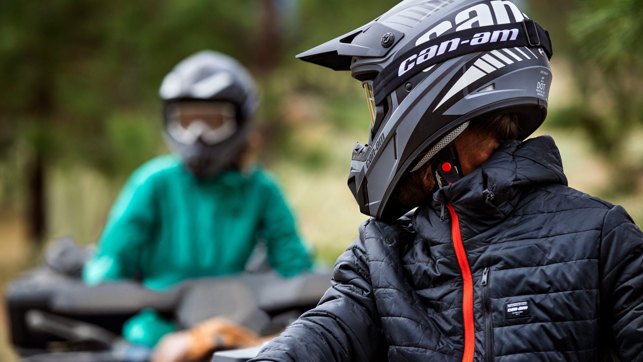 2 people with Can-Am helmets talking during an ATV ride