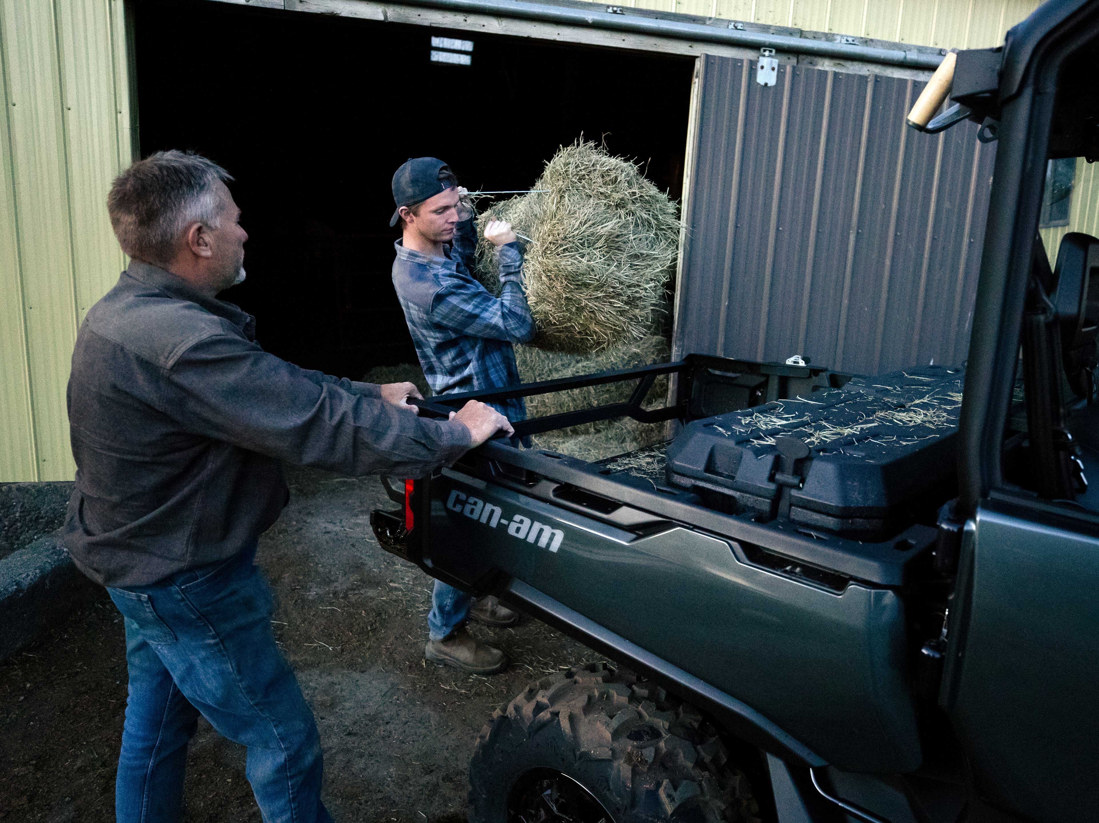 Father and son loading hay blocks on a Defender bed