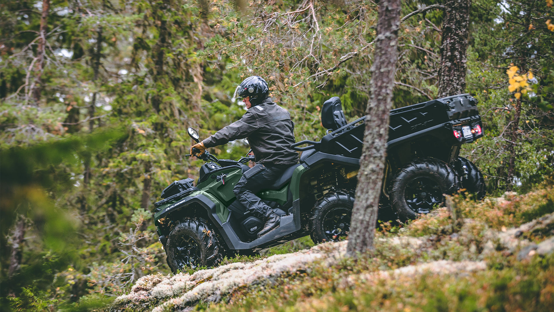 Jazdec jazdí na jeho boreal green Can-Am 6x6 Outlander dolu kopcom