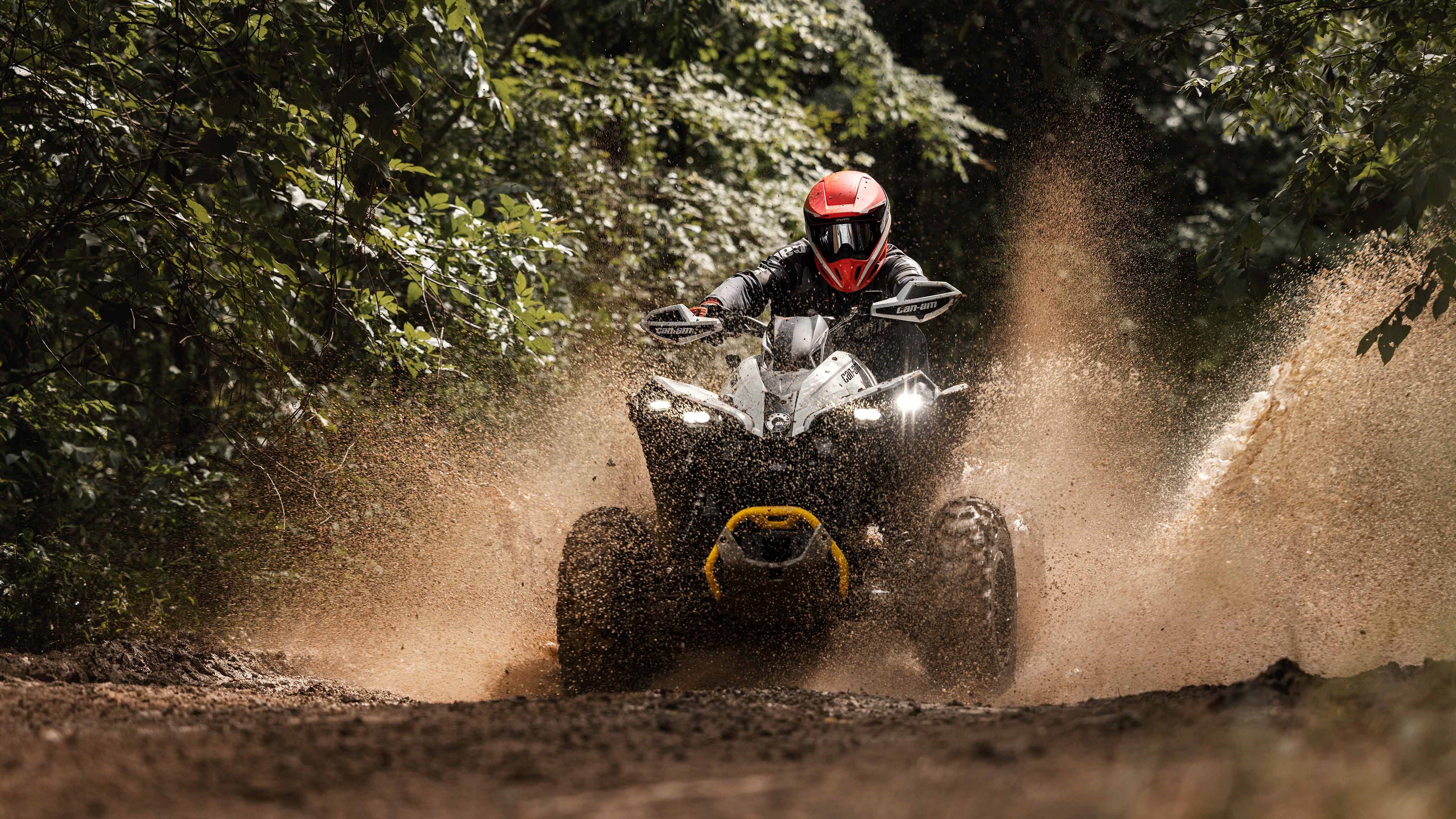 A Can-Am Renegade X MR 1000 ATV riding on a muddy trail