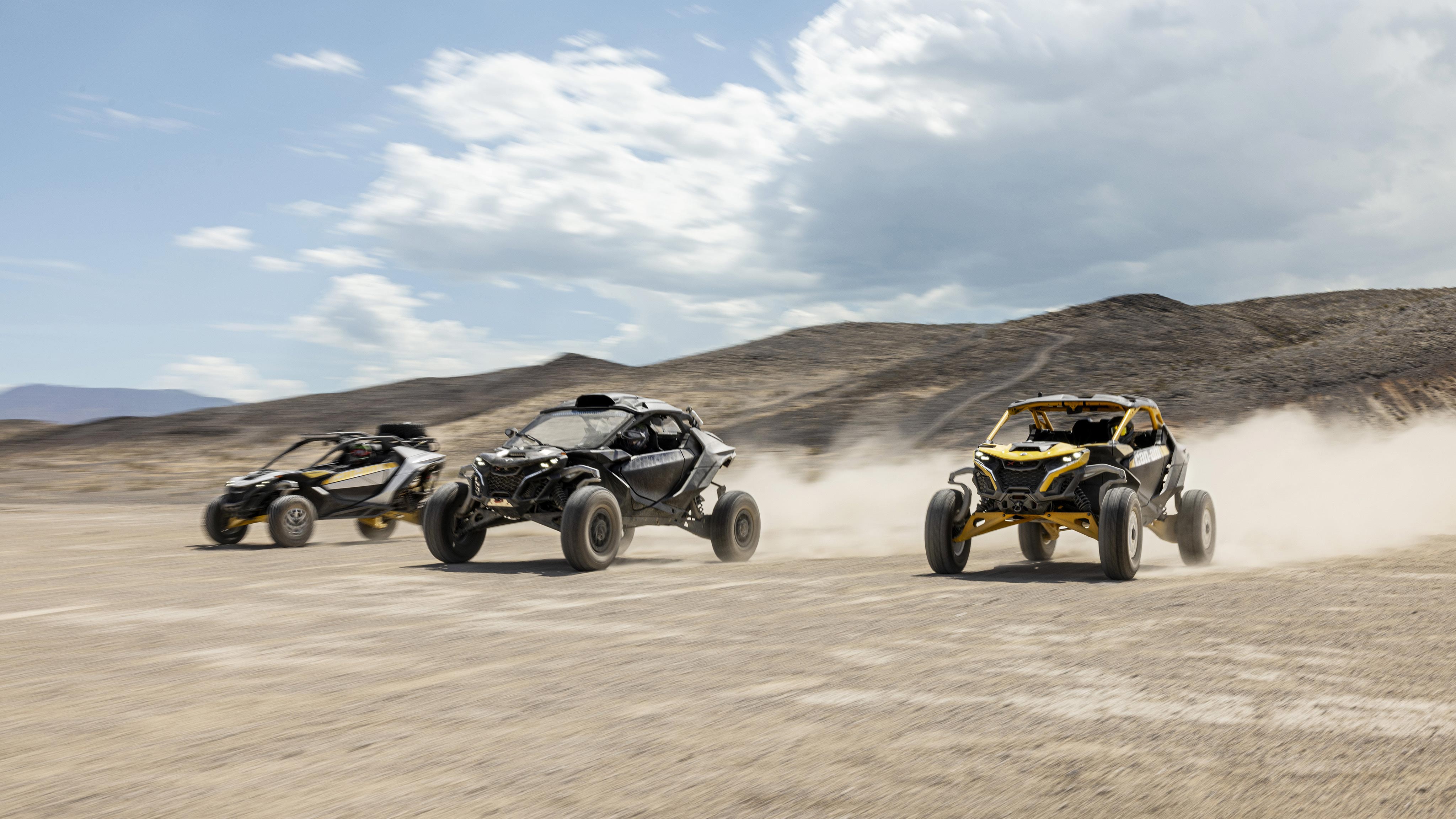 Three Can-Am Off-Road SxS vehicles racing through the desert