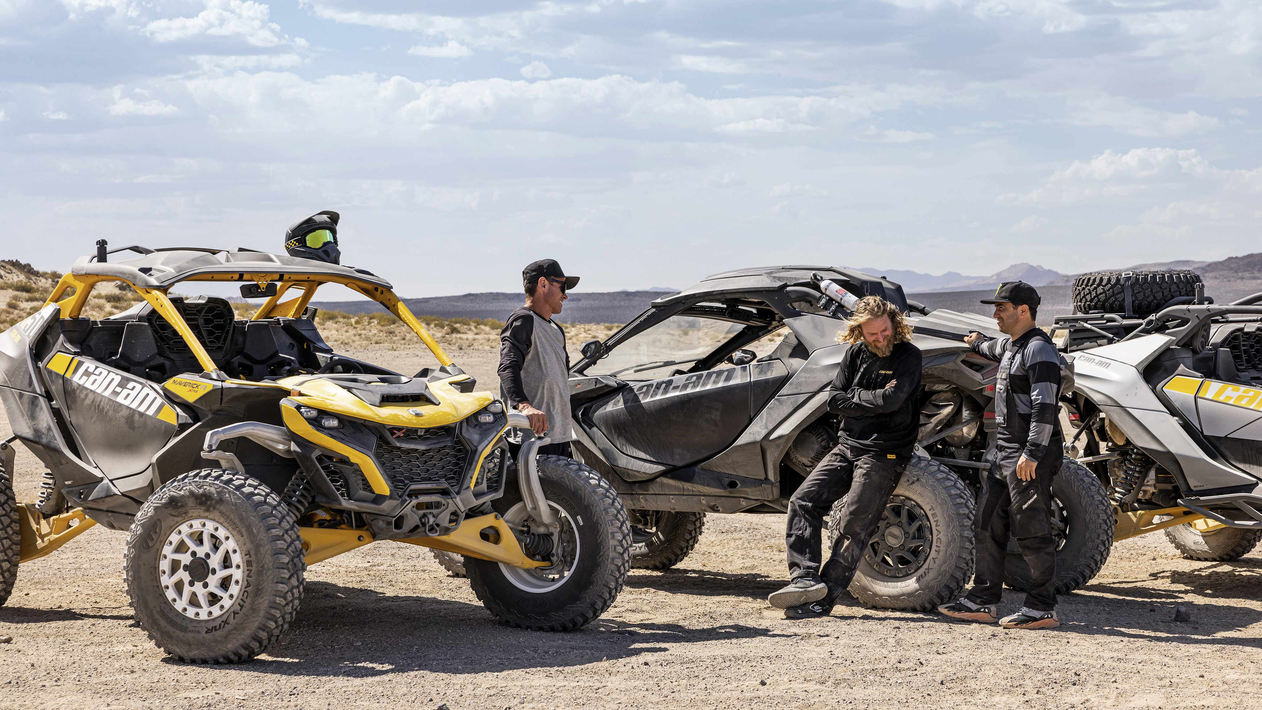 Three riders taking a break with their three Maverick SxS vehicles