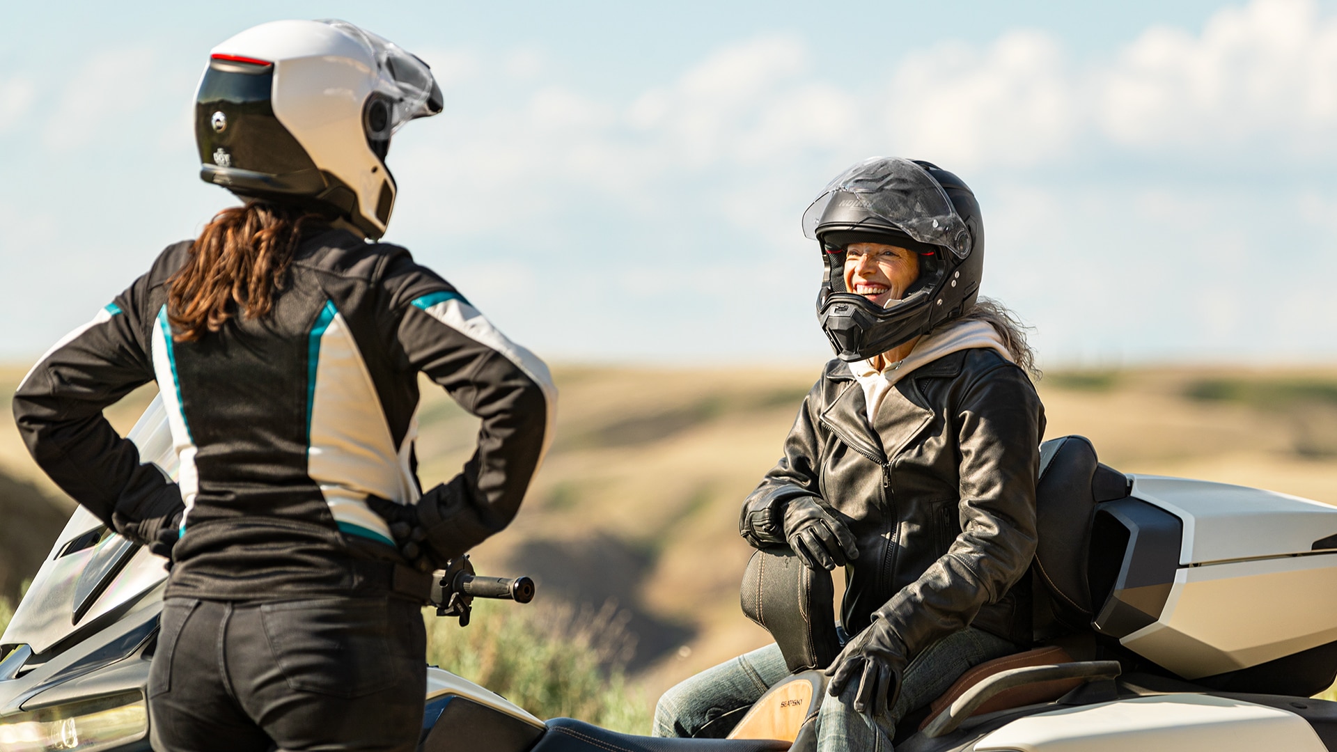 2024 Can-Am Ryker motosikletlerinin yanında İki sürücünün sohbet eden bir grup sürücü