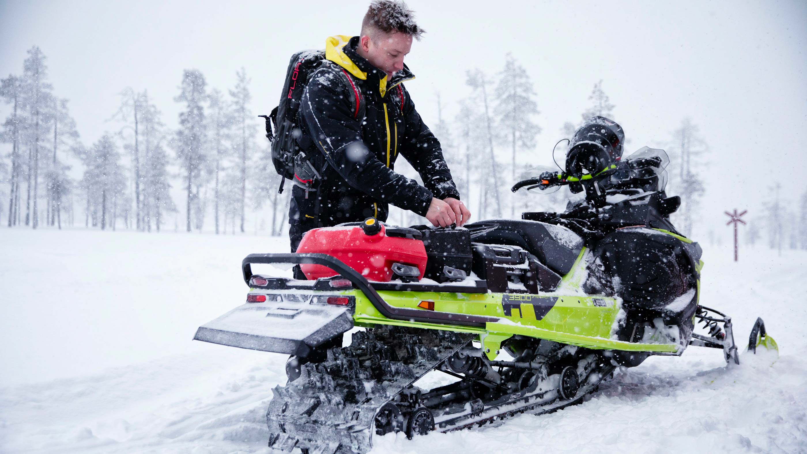 Man opening a LinQ bag mounted on a Lynx Xterrain snowmobile