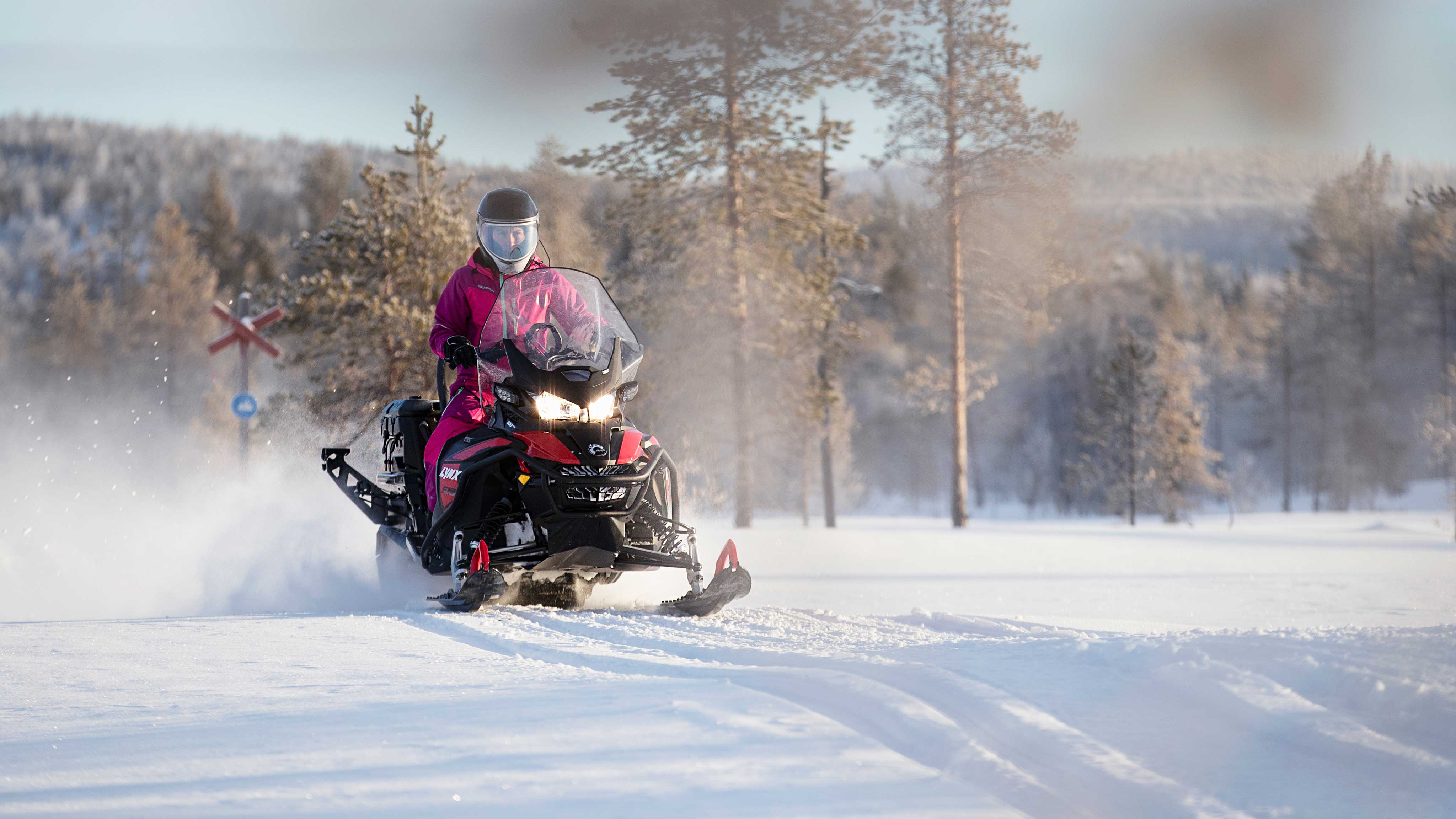 Person riding Lynx 59 Ranger snowmobile on a trail