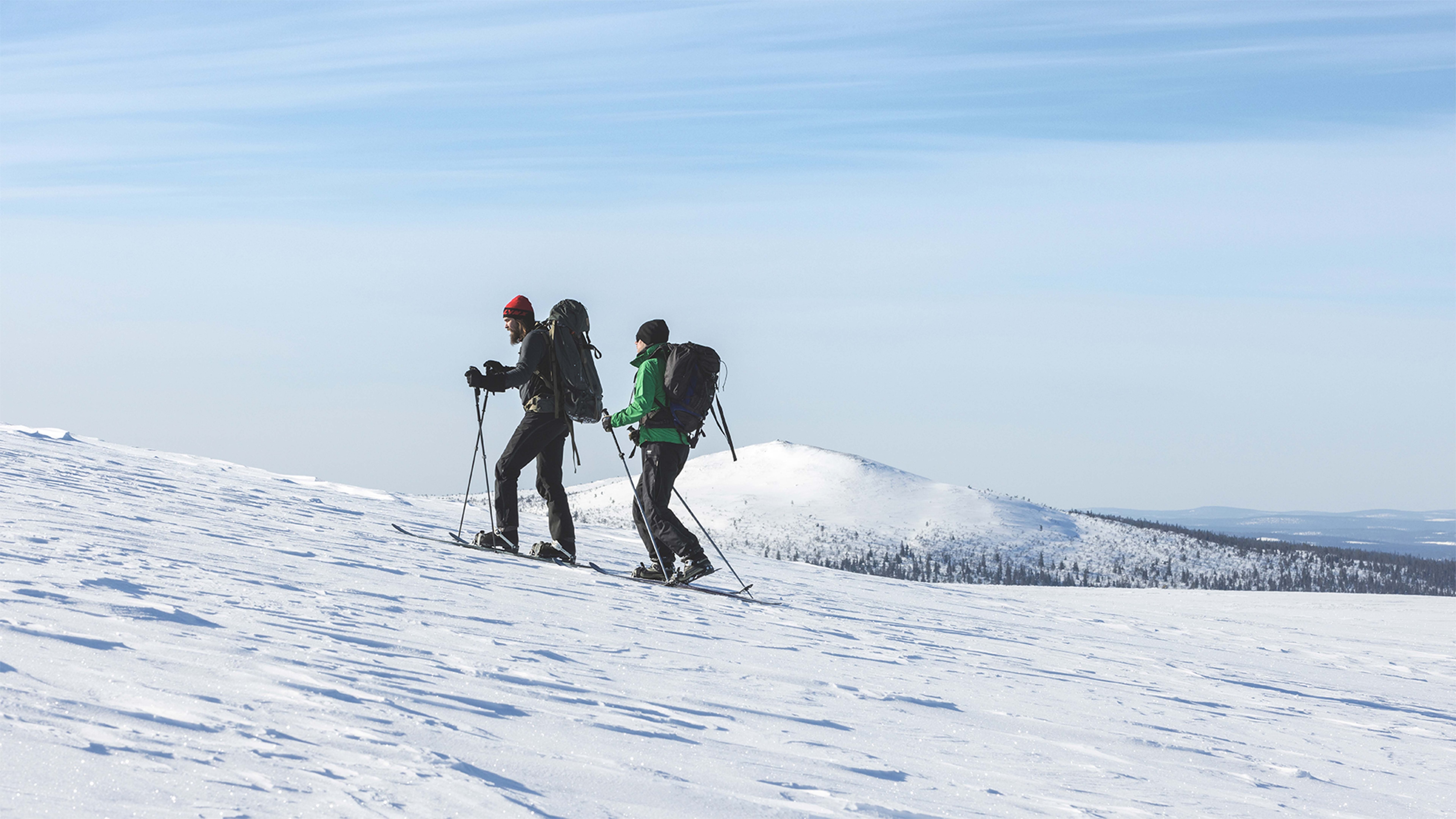 Two men ski on the top of the fell