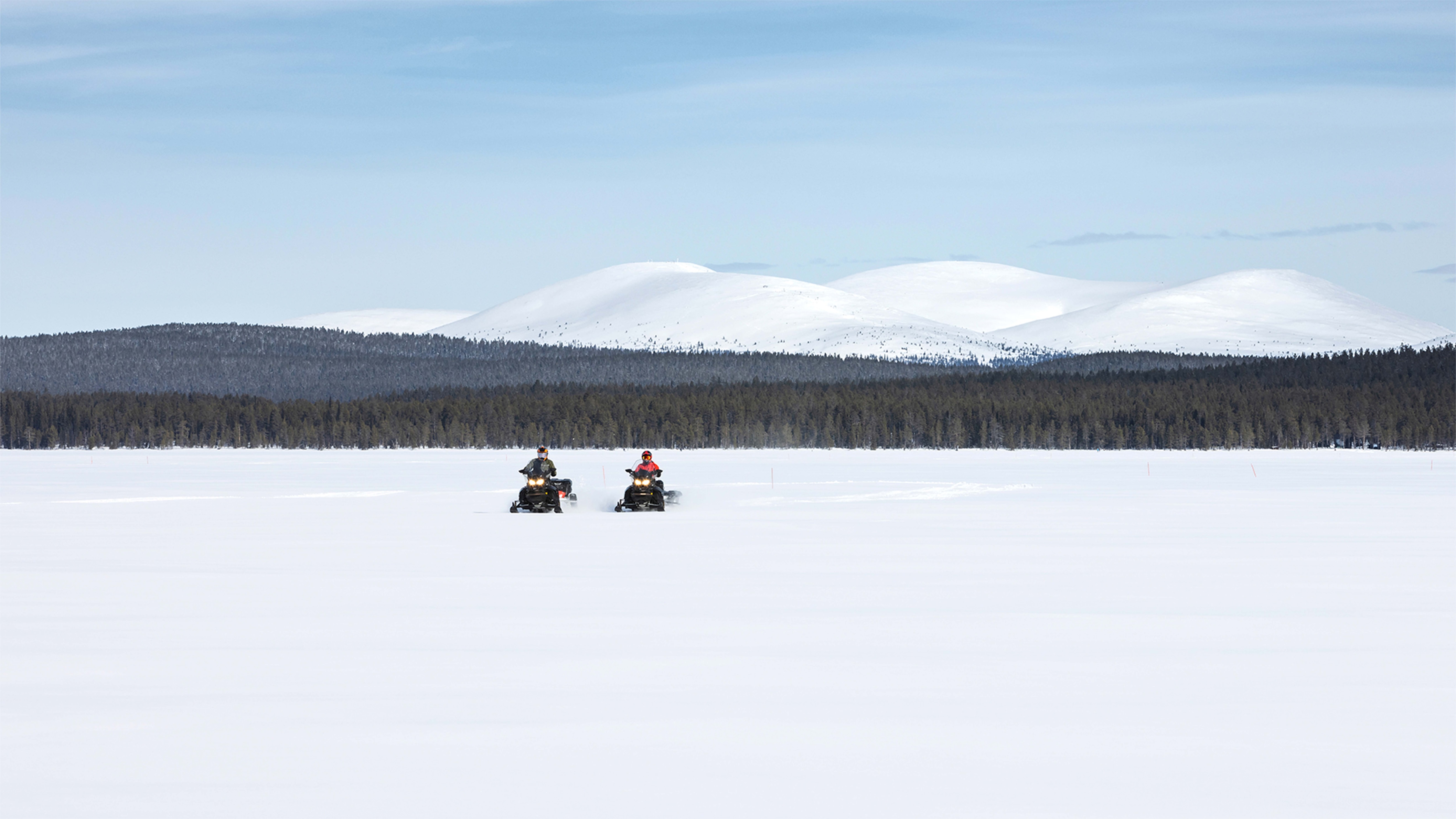 Two Lynx 49 Ranger ST and Commander Grand Tourer snowmobiles ride on the lake in Finnish Lapland