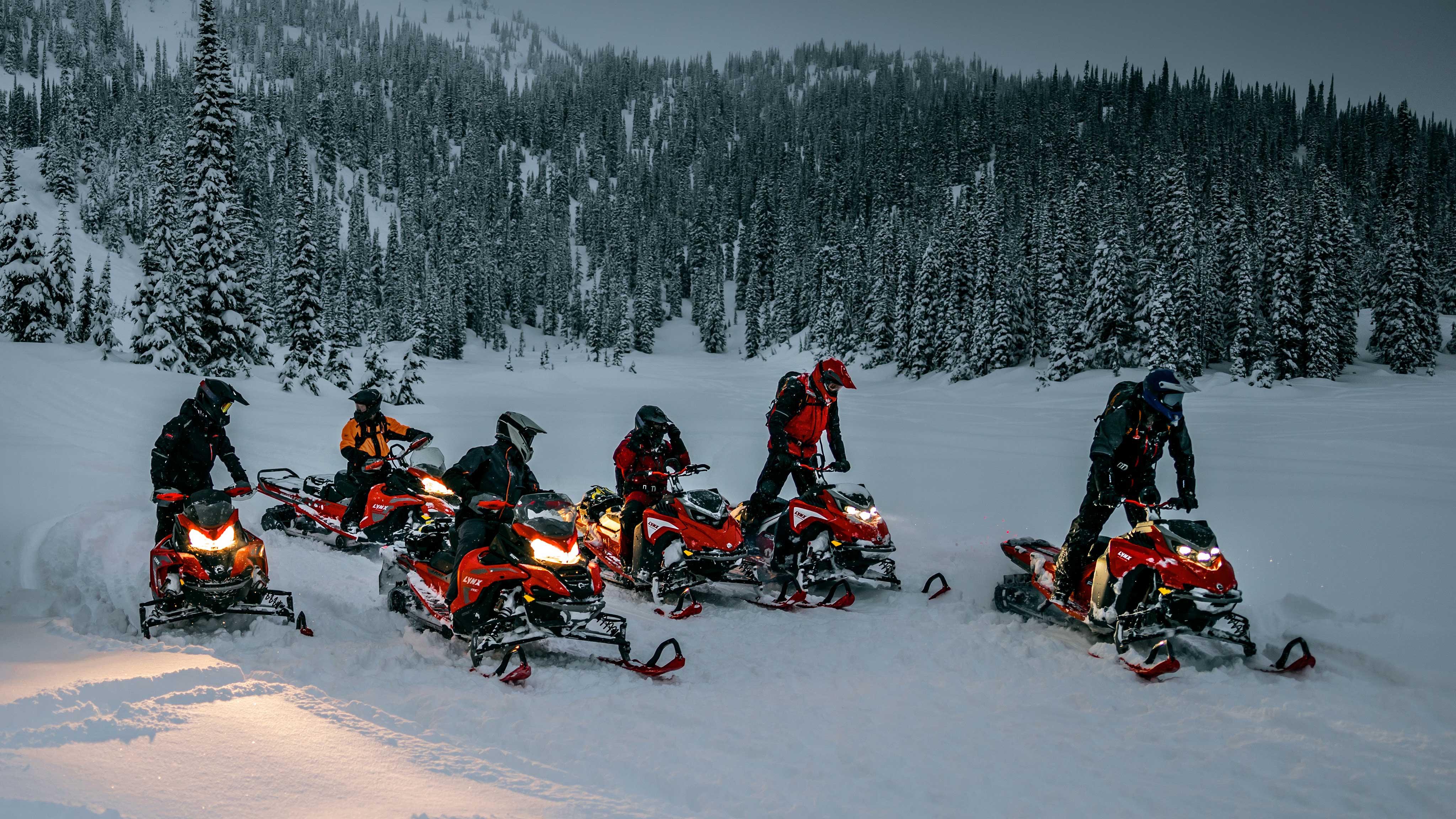 Group of riders taking a short break with their Lynx Snowmobile during a nightly ride