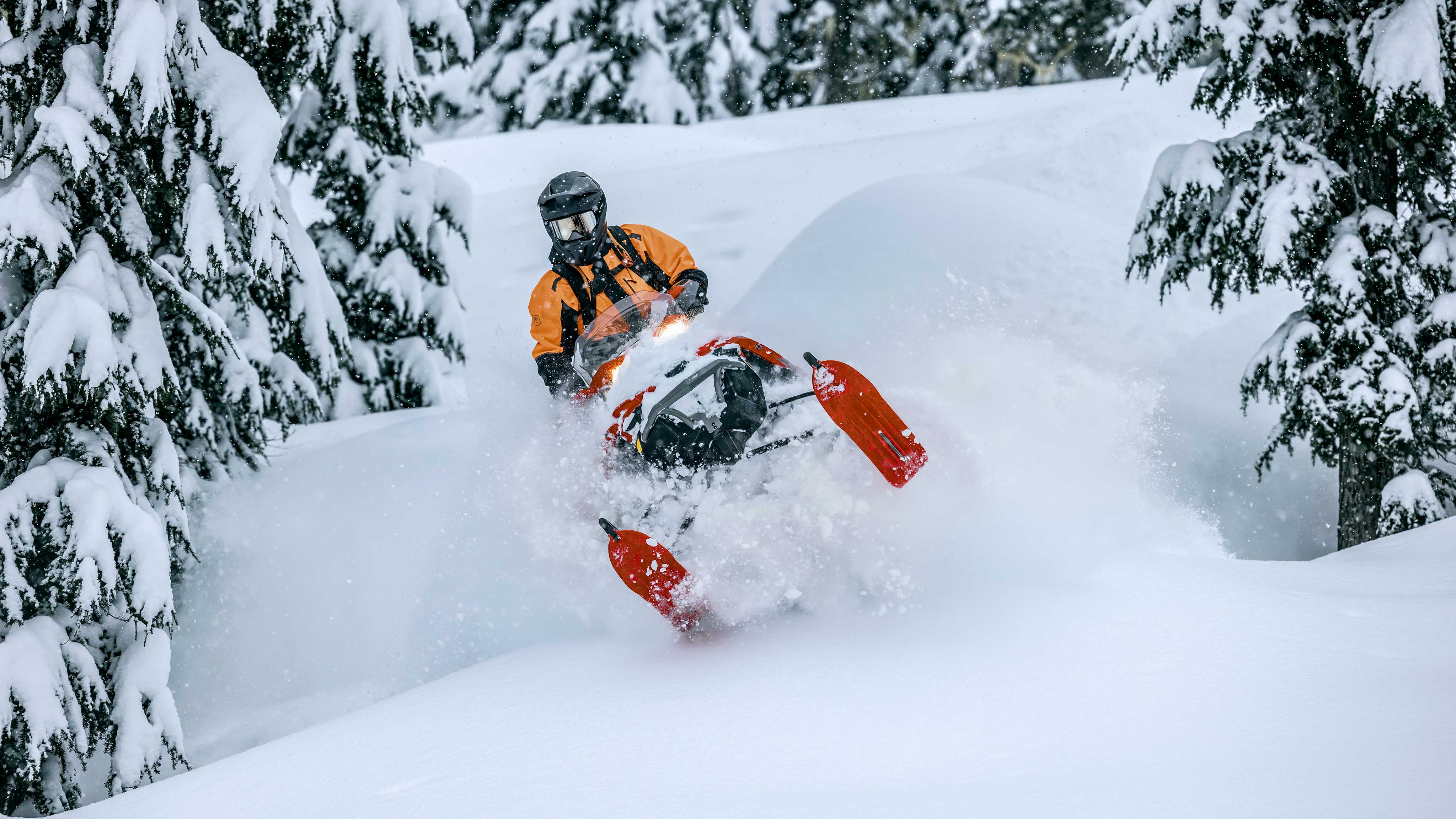 Lynx snowmobile rider driving downhill of a snowy mountain