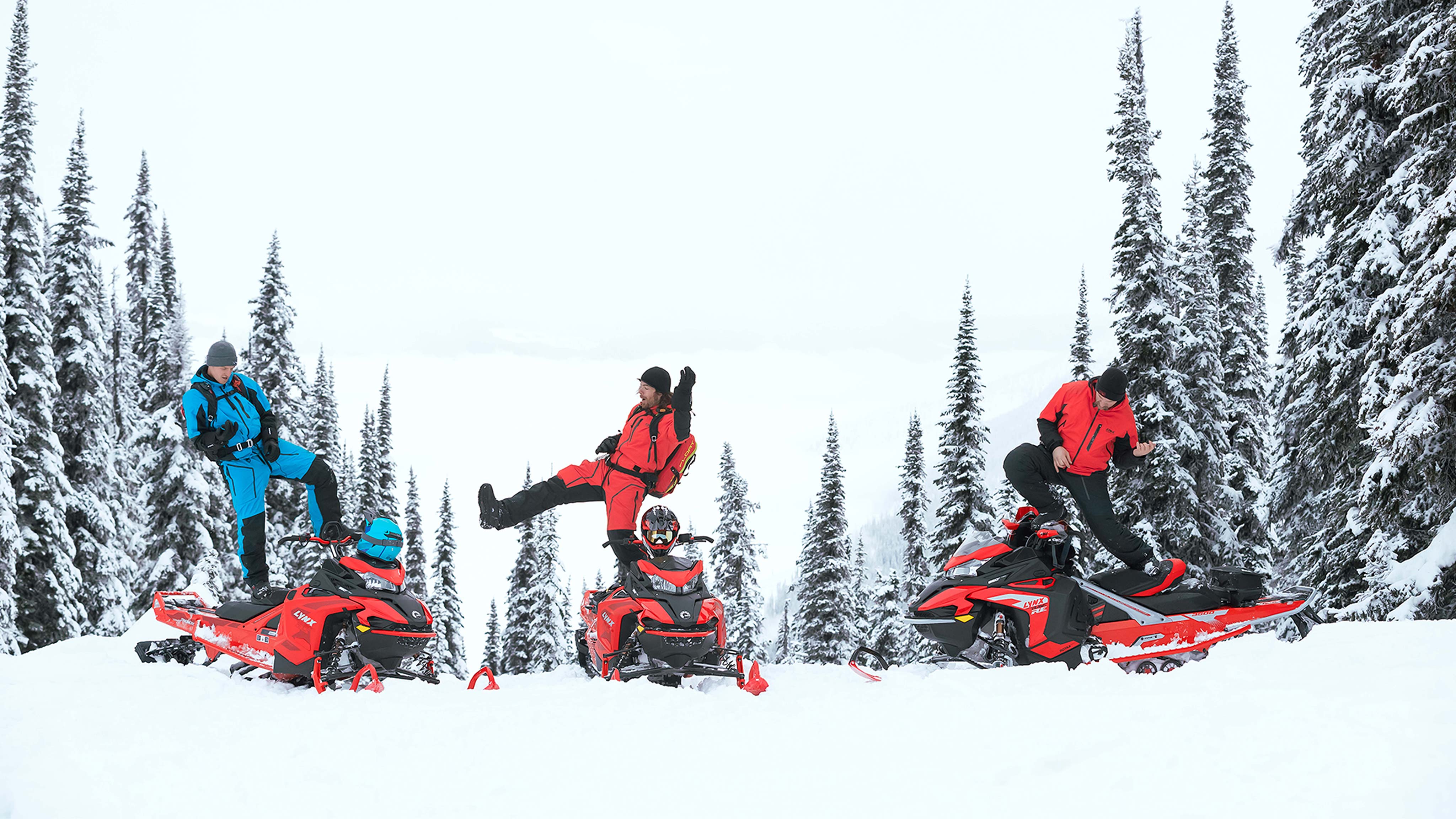 Three men playing air guitar on a Lynx BoonDocker snowmobiles at mountains