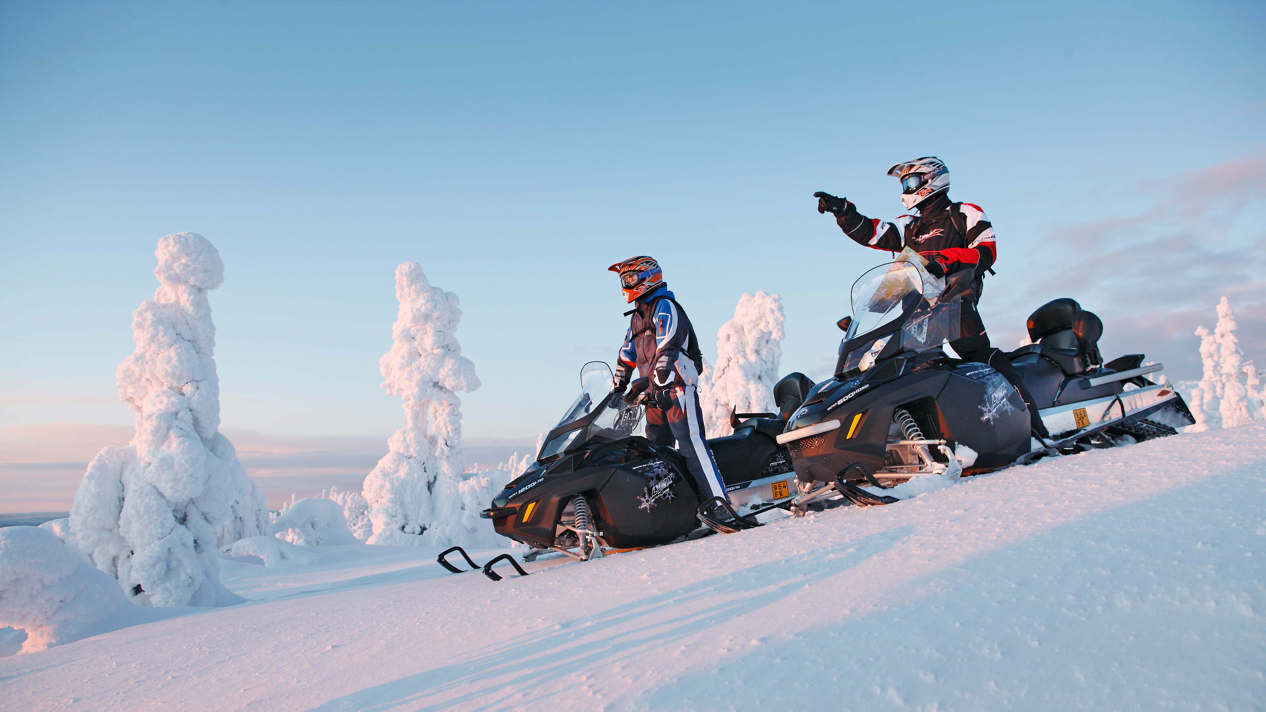 Muži stoja na skútroch Lynx Adventure Grand Tourer a pozerajú sa na krajinu