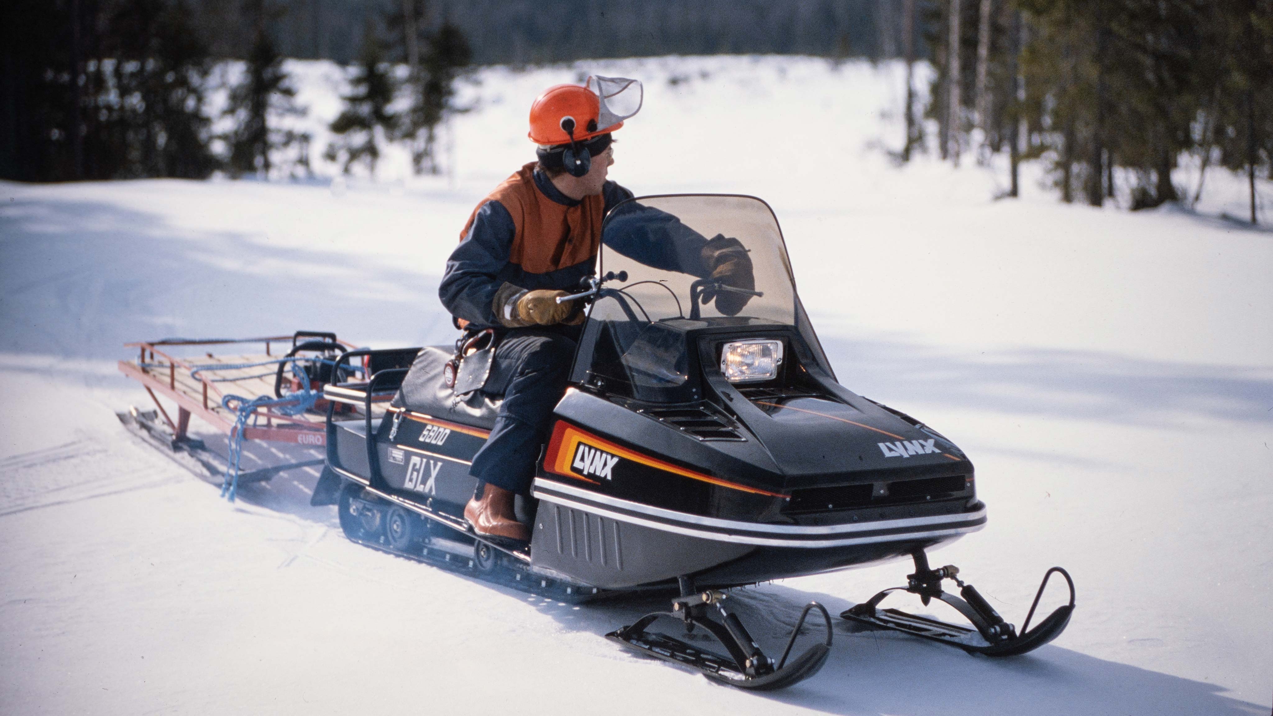 Muž ťahá vybavenie na saniach za skútrom Lynx GLX 5900 1986 