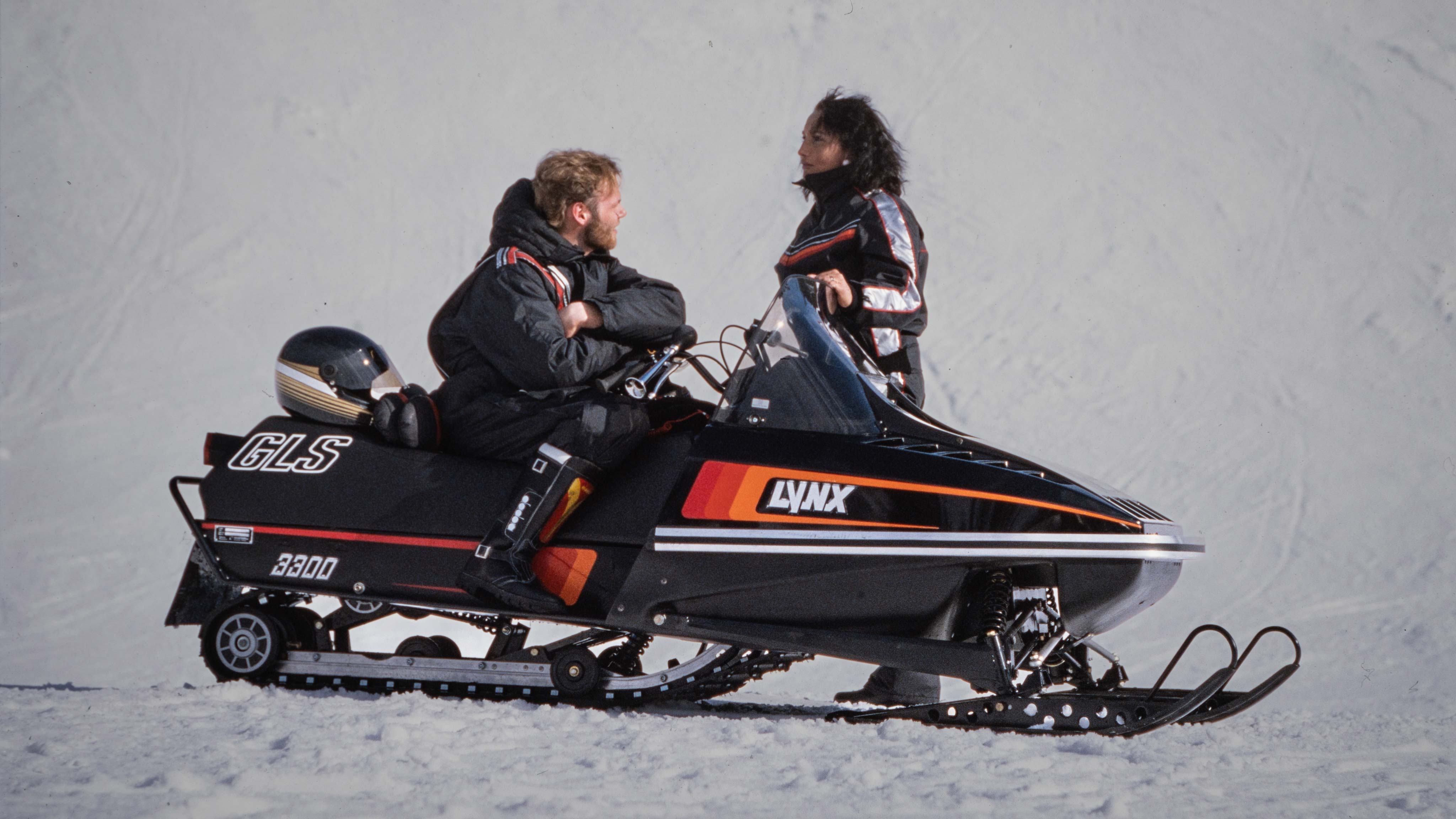 Couple chatting on Lynx GLS 3300 1985 snowmobile