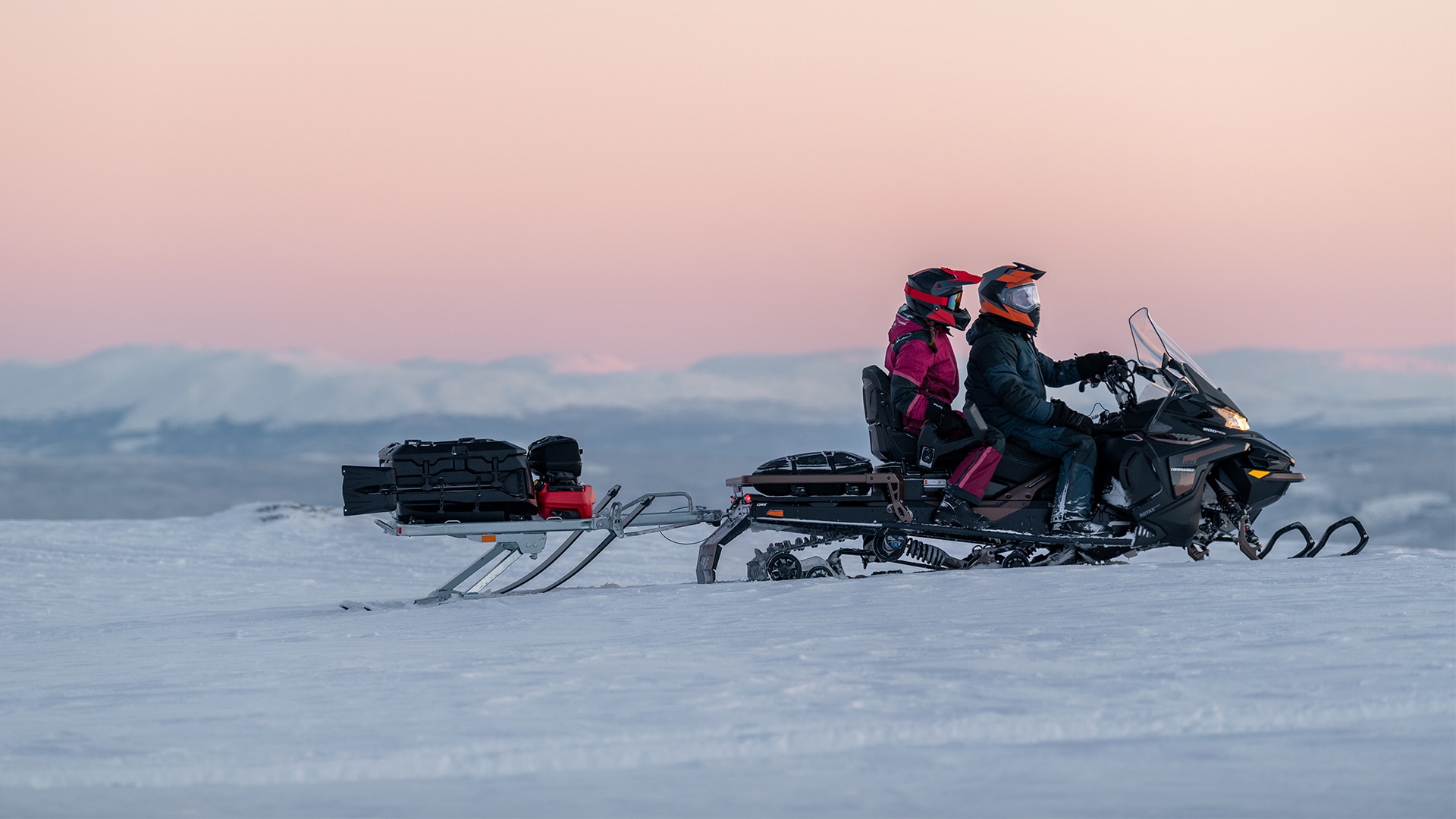 Couple riding with Lynx Commander Grand Tourer snowmobile on the mountains