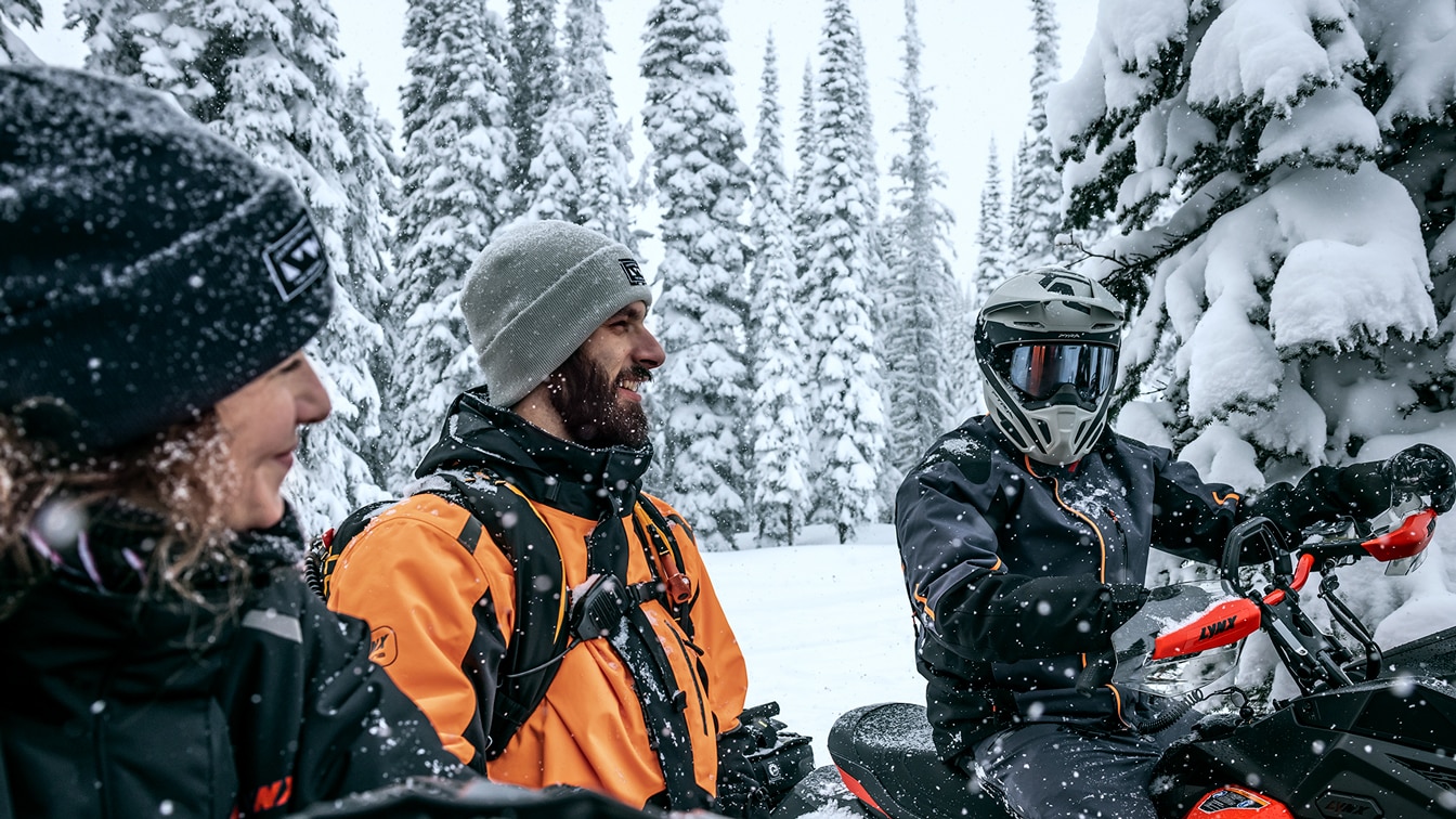 Three riders having break on snowmobiles