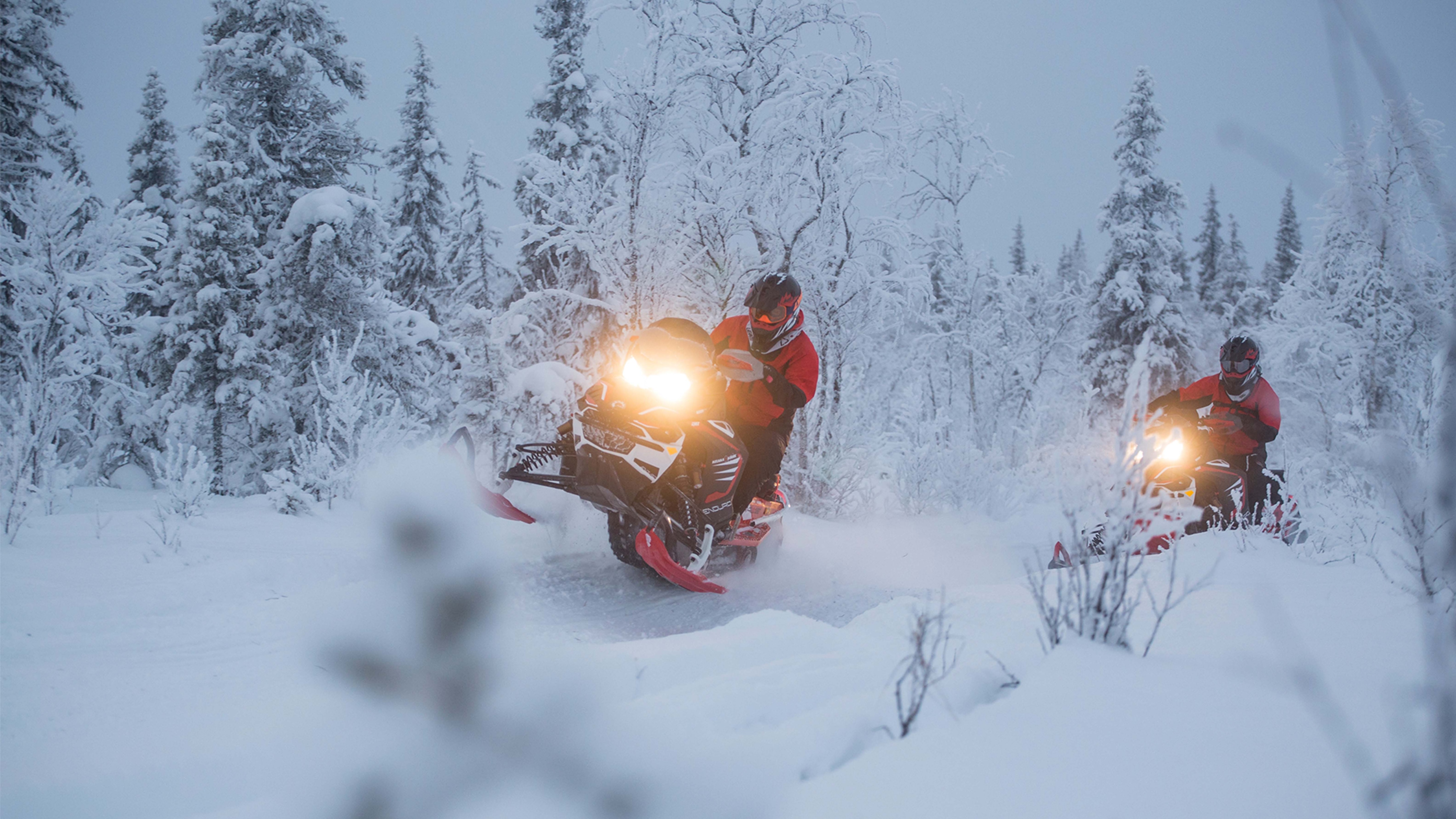 Two Lynx Rave Enduro snowmobiles accelerating on trail