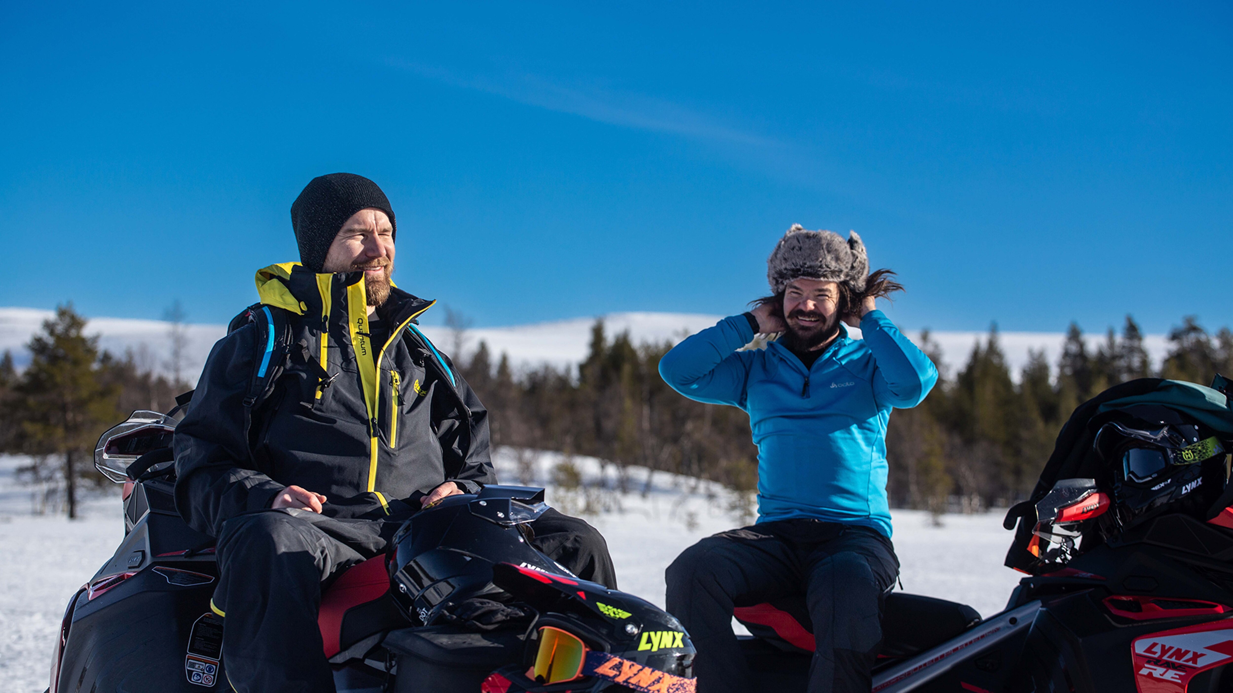 Janne Kaperi and Kaitsu Rinkinen from Biisonimafia chatting and laughing on snowmobiles