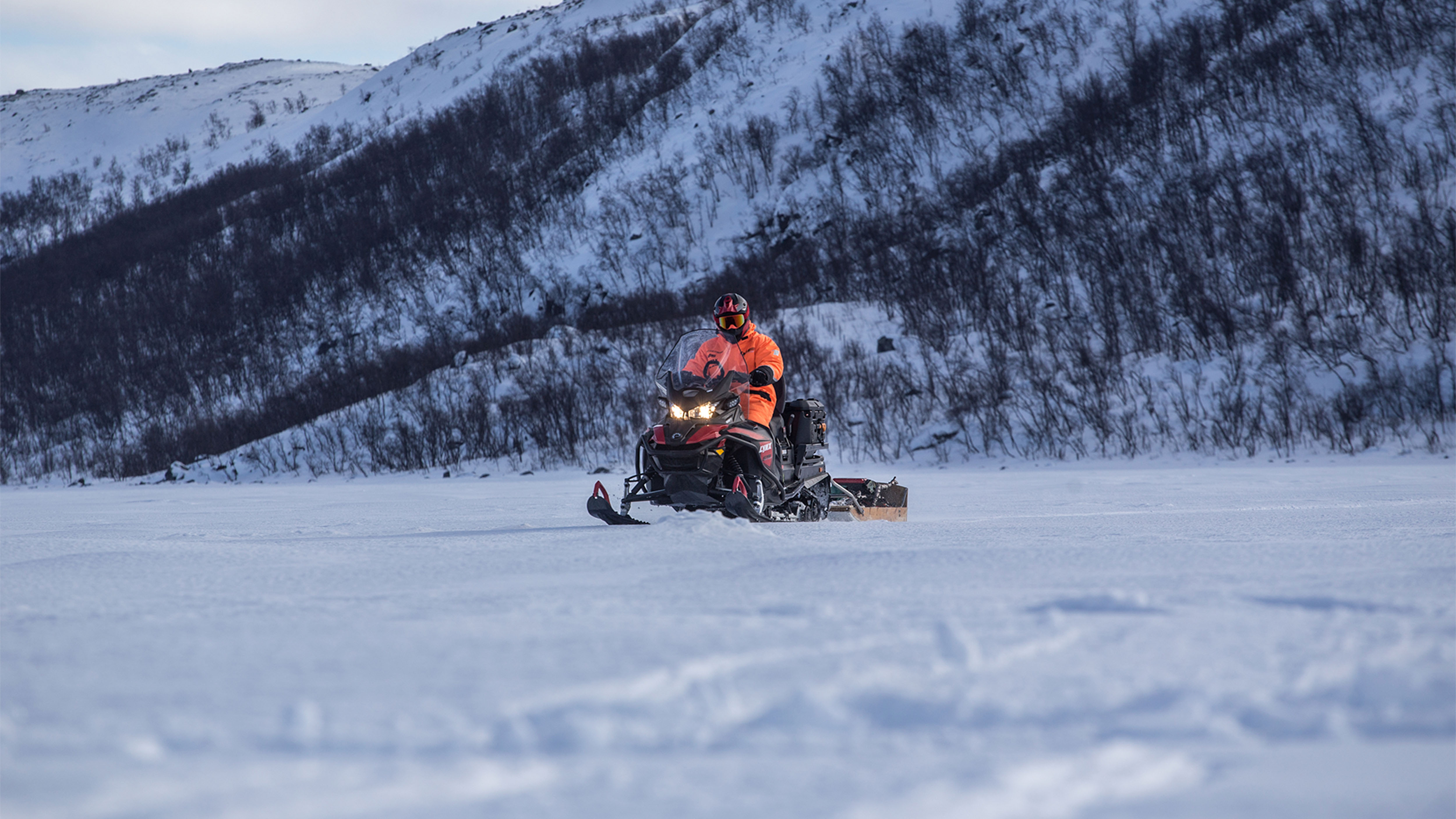 Snežný skúter Lynx 59 Ranger ťahá sane na zamrznutom jazere