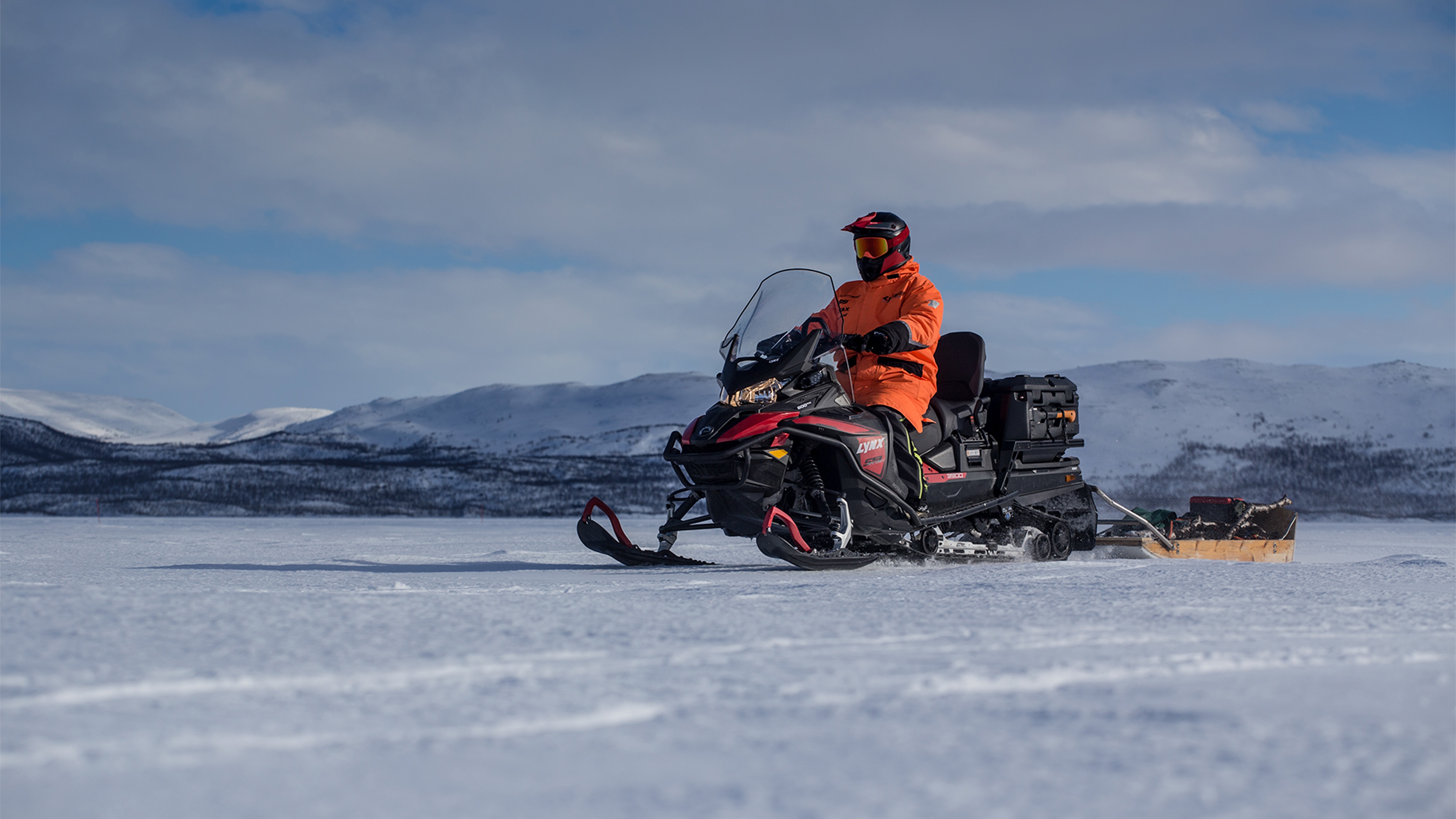 Lynx 59 Ranger snowmobile towing sleigh on lakeice