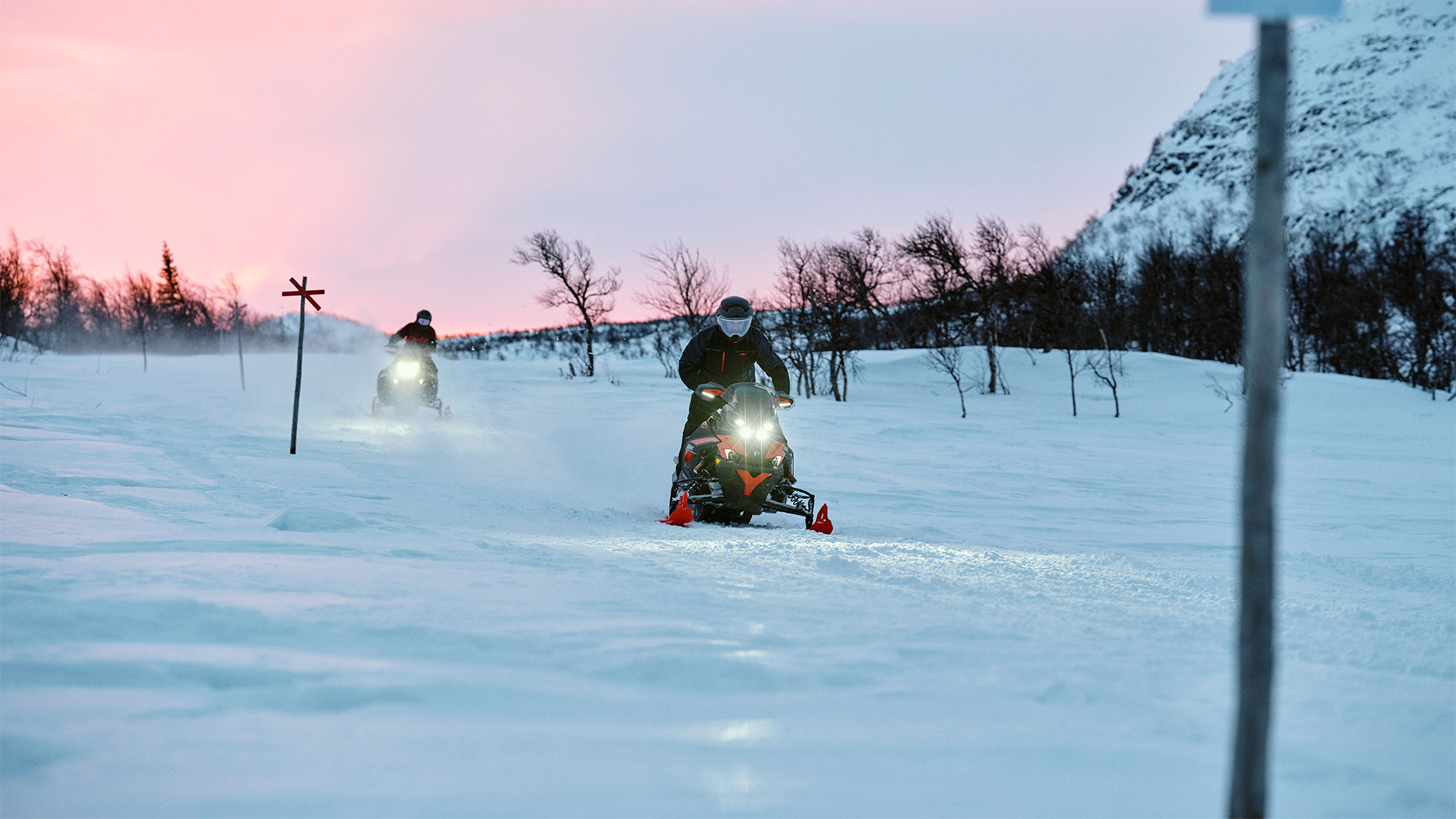 Dva snežné skútre Lynx Xterrain RE 2025 jazdia po traili pri východe slnka