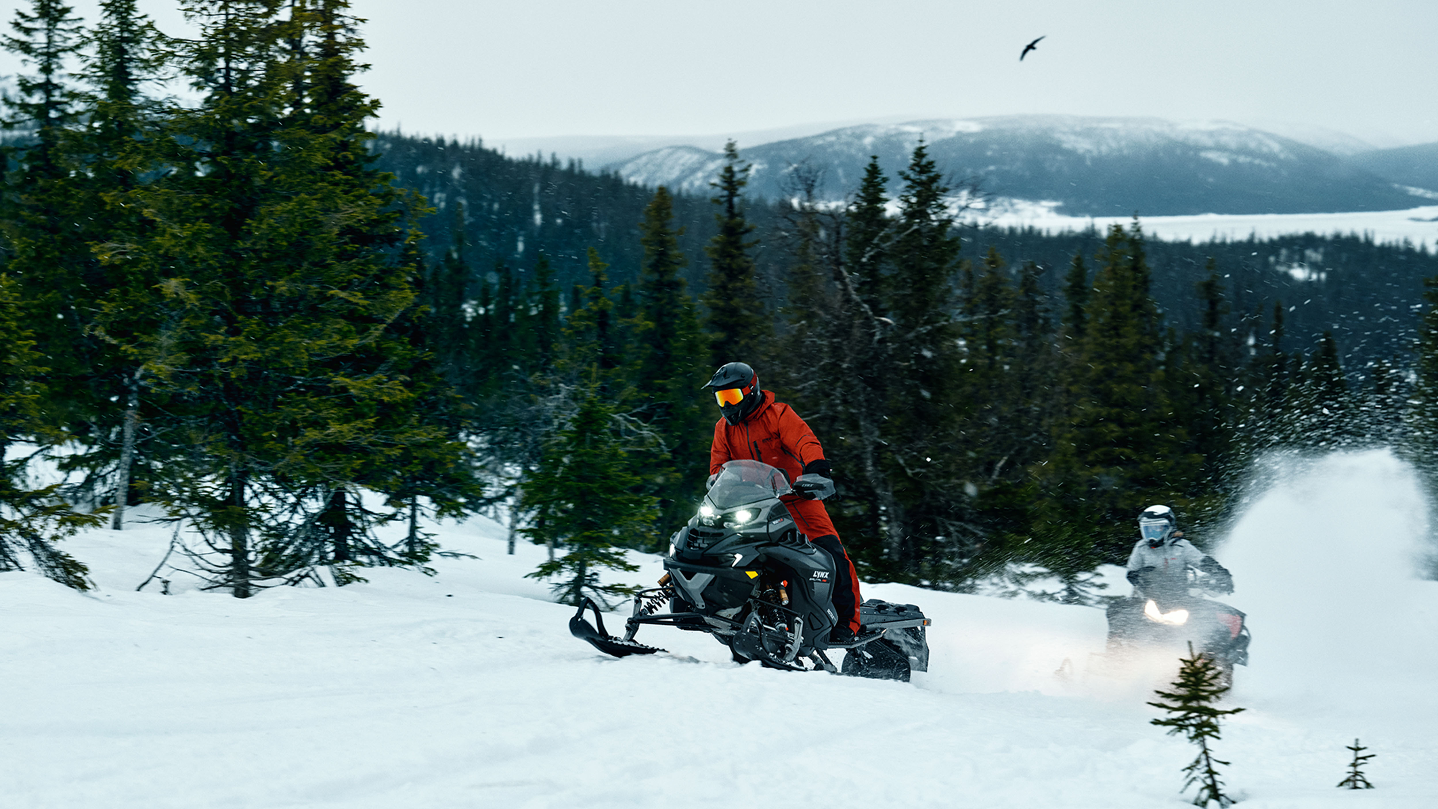 Two Lynx Brutal RE 2025 snowmobiles riding uphill on trail