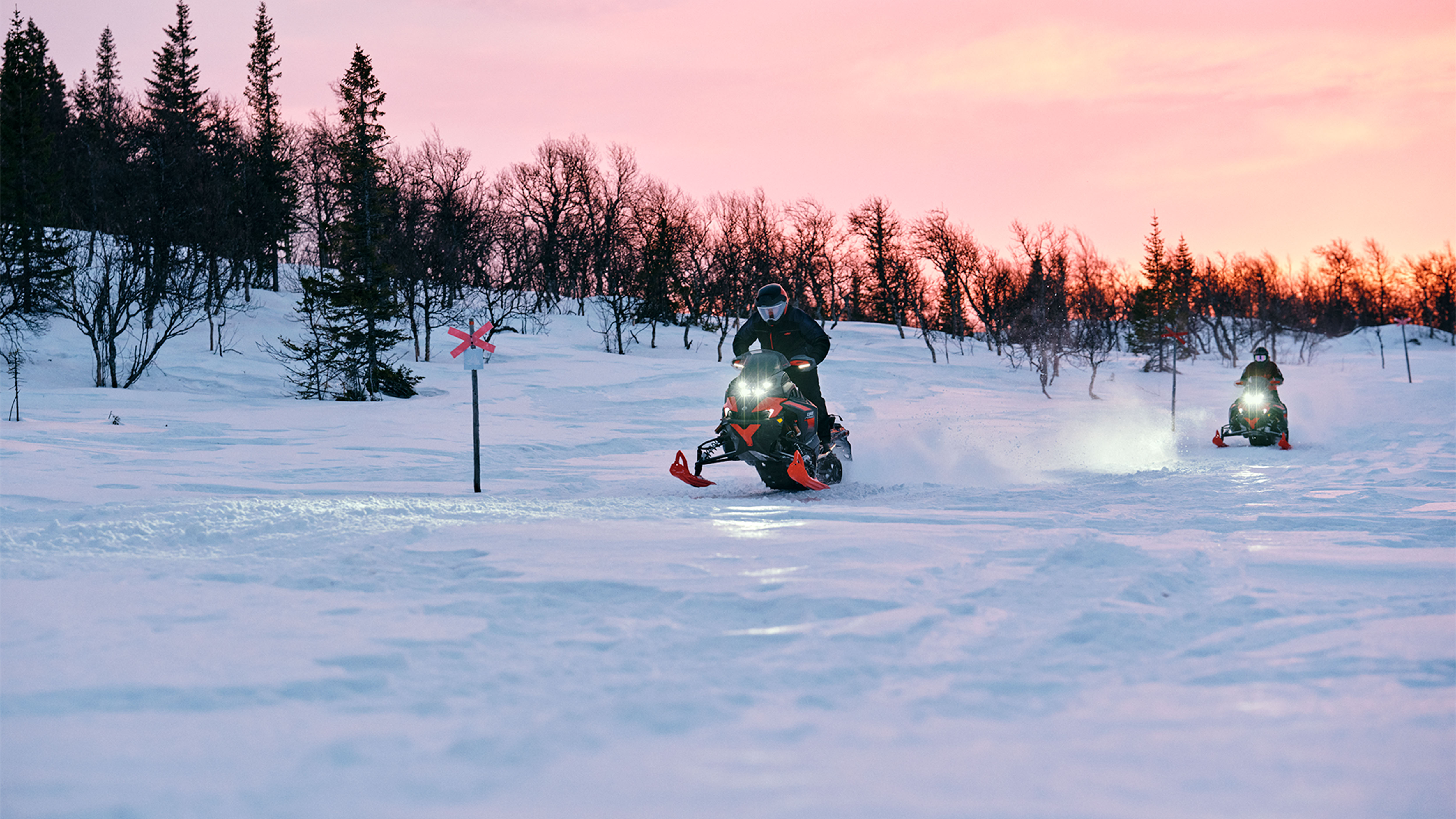 Dva snežné skútre Lynx Xterrain RE 2025 jazdia po traili pri východe slnka