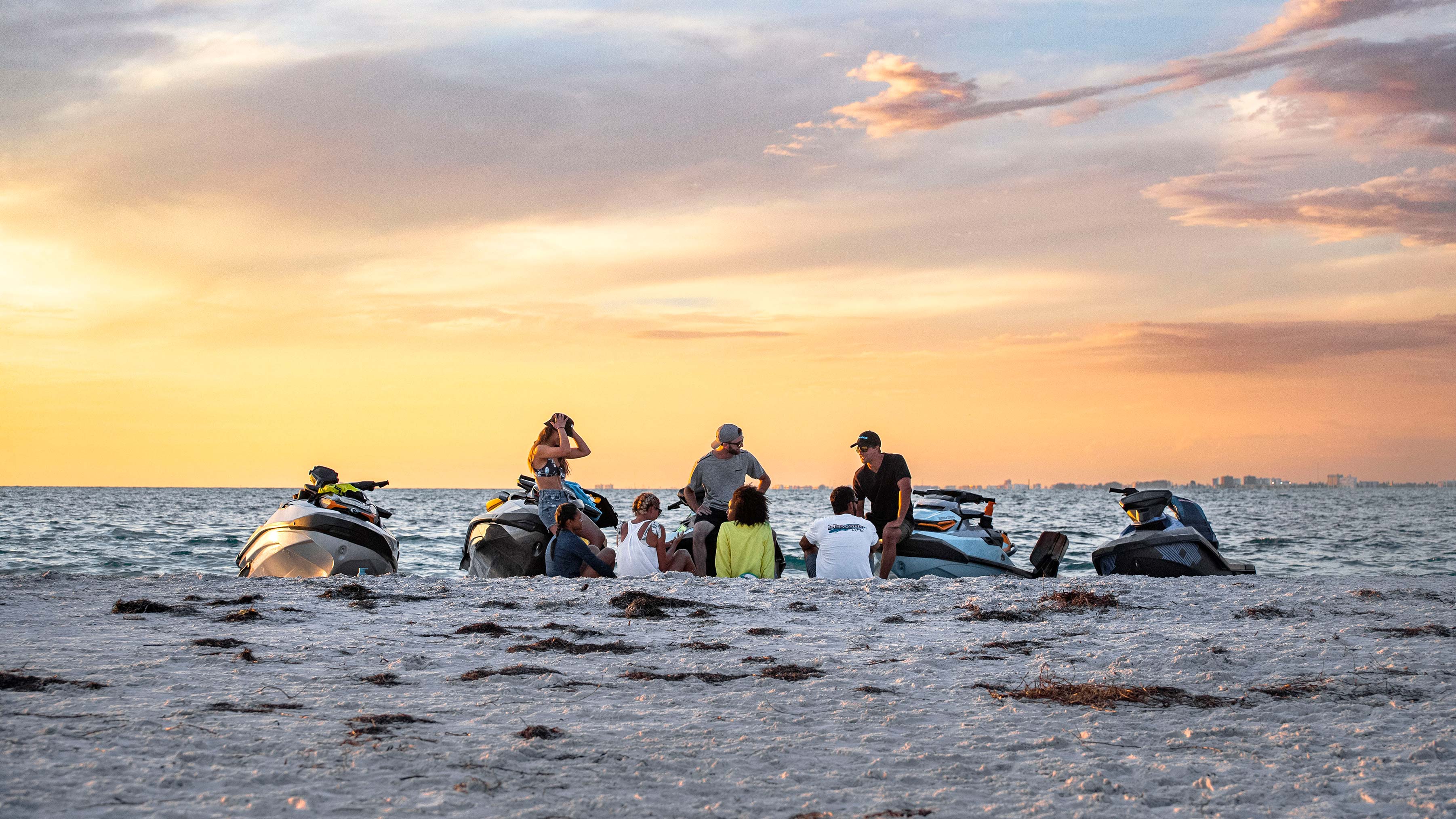 Skupina kamarátov na pláži s vodnými skútrami Sea-Doo 