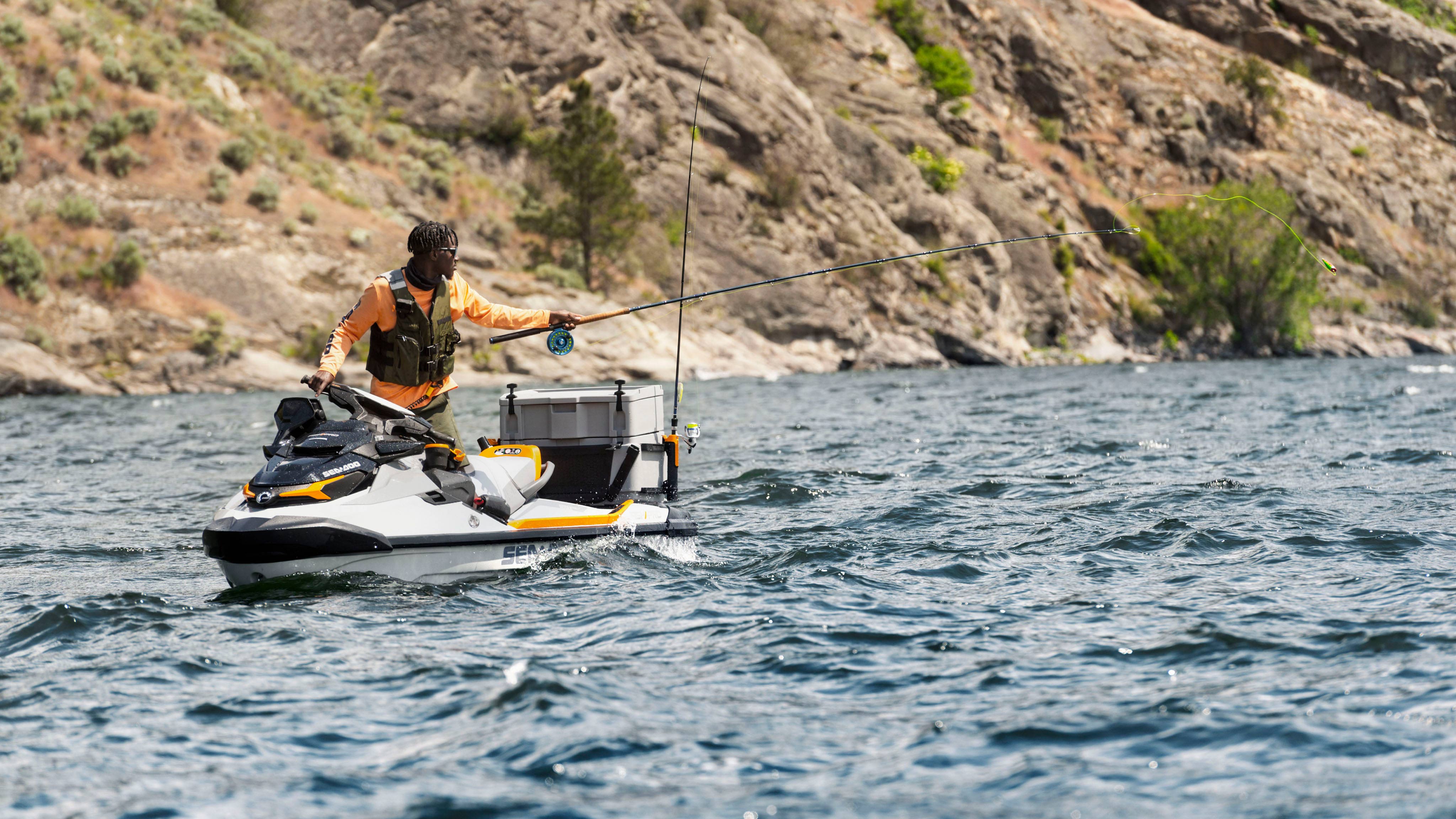 Emmanuel Williams fishing on while holding the handlebars of the Sea-Doo FishPro Trophy