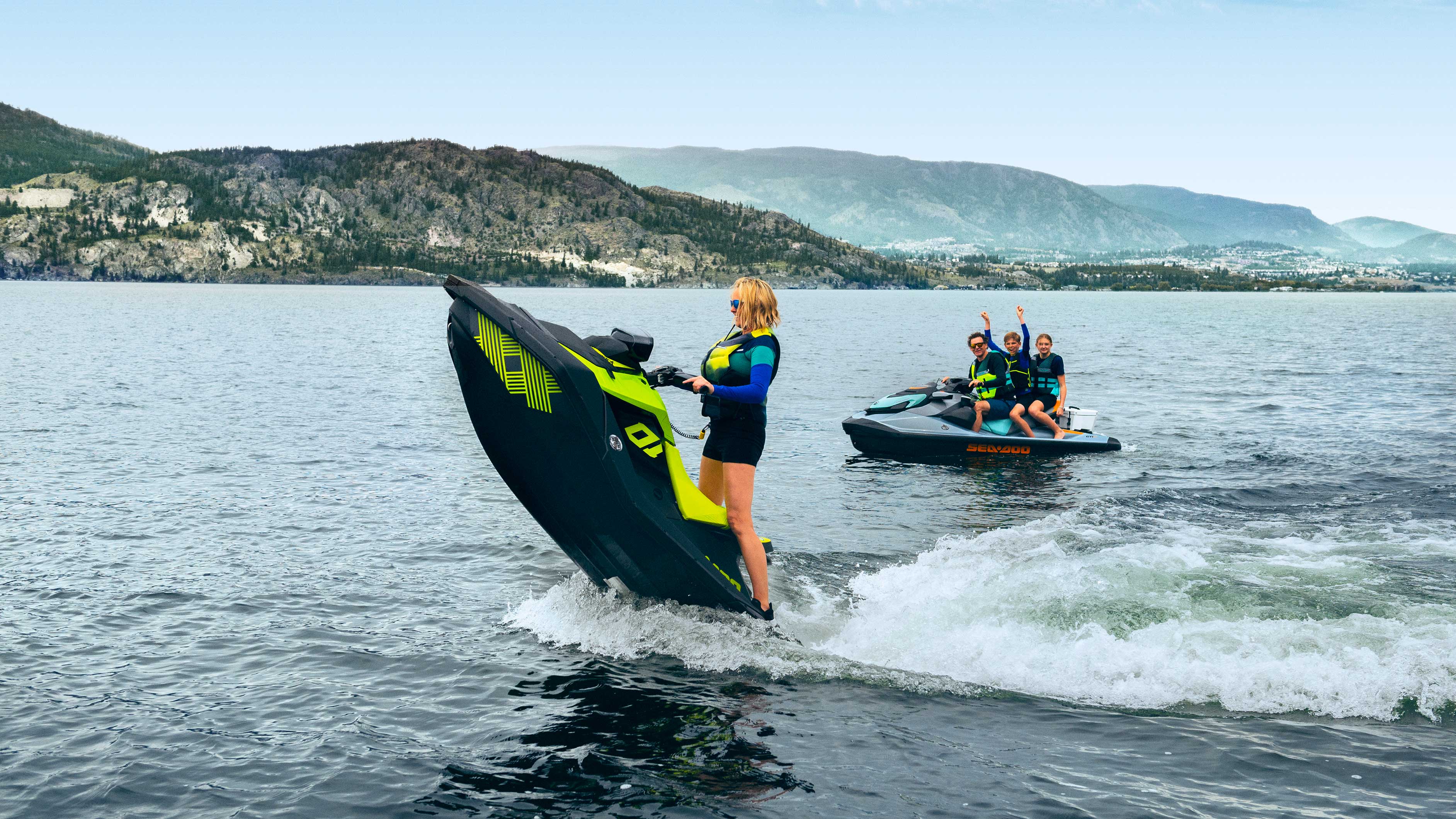 Žena zdvíha nos skútra Spark Trixx a zvyšok jej rodiny jazdí na GTI SE