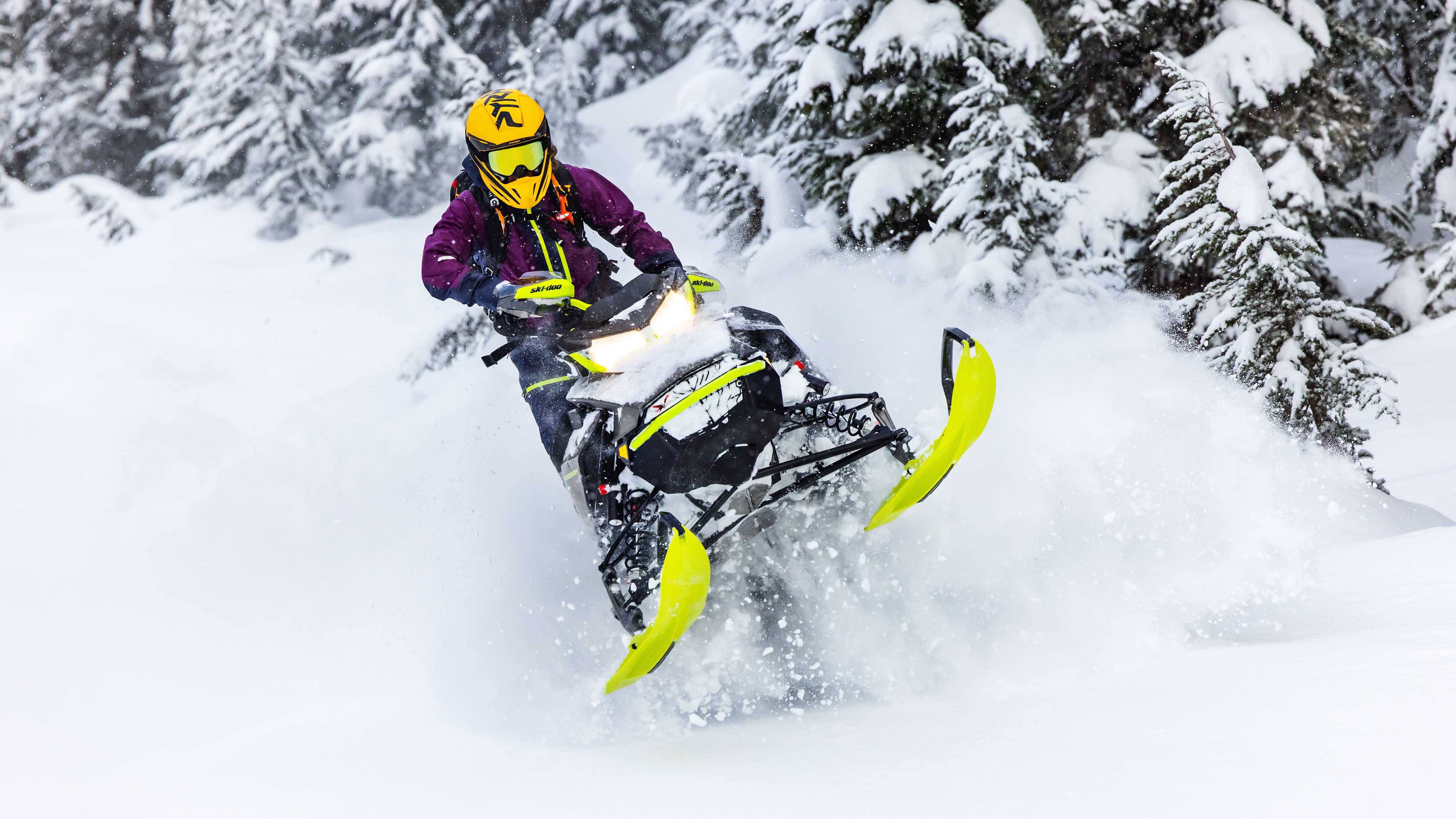 Жена која вози во длабочините на планинскиот снег со својата Ski-Doo моторна санка