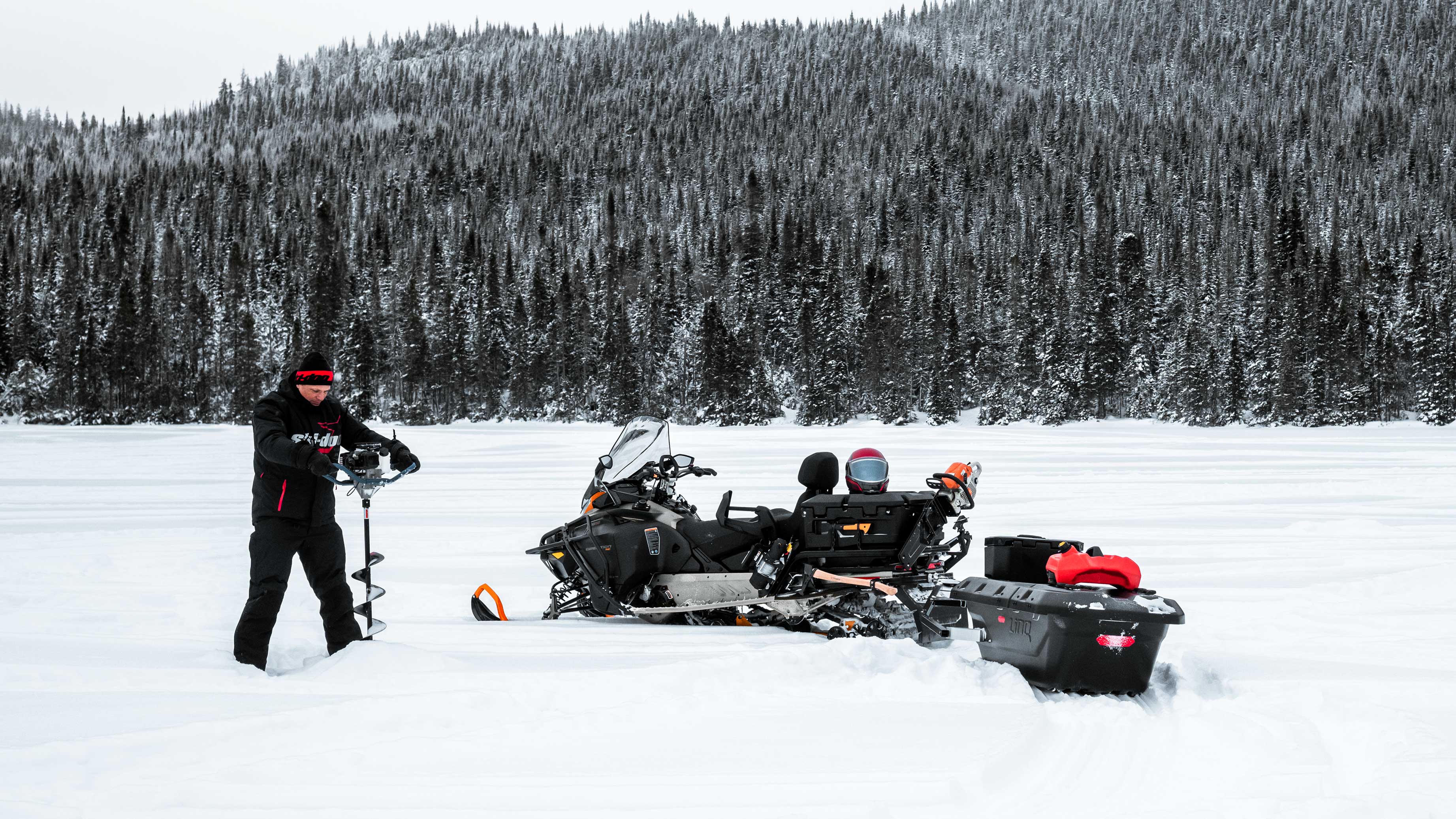 Man Ice fishing on a lake with his Ski-Doo Expedition