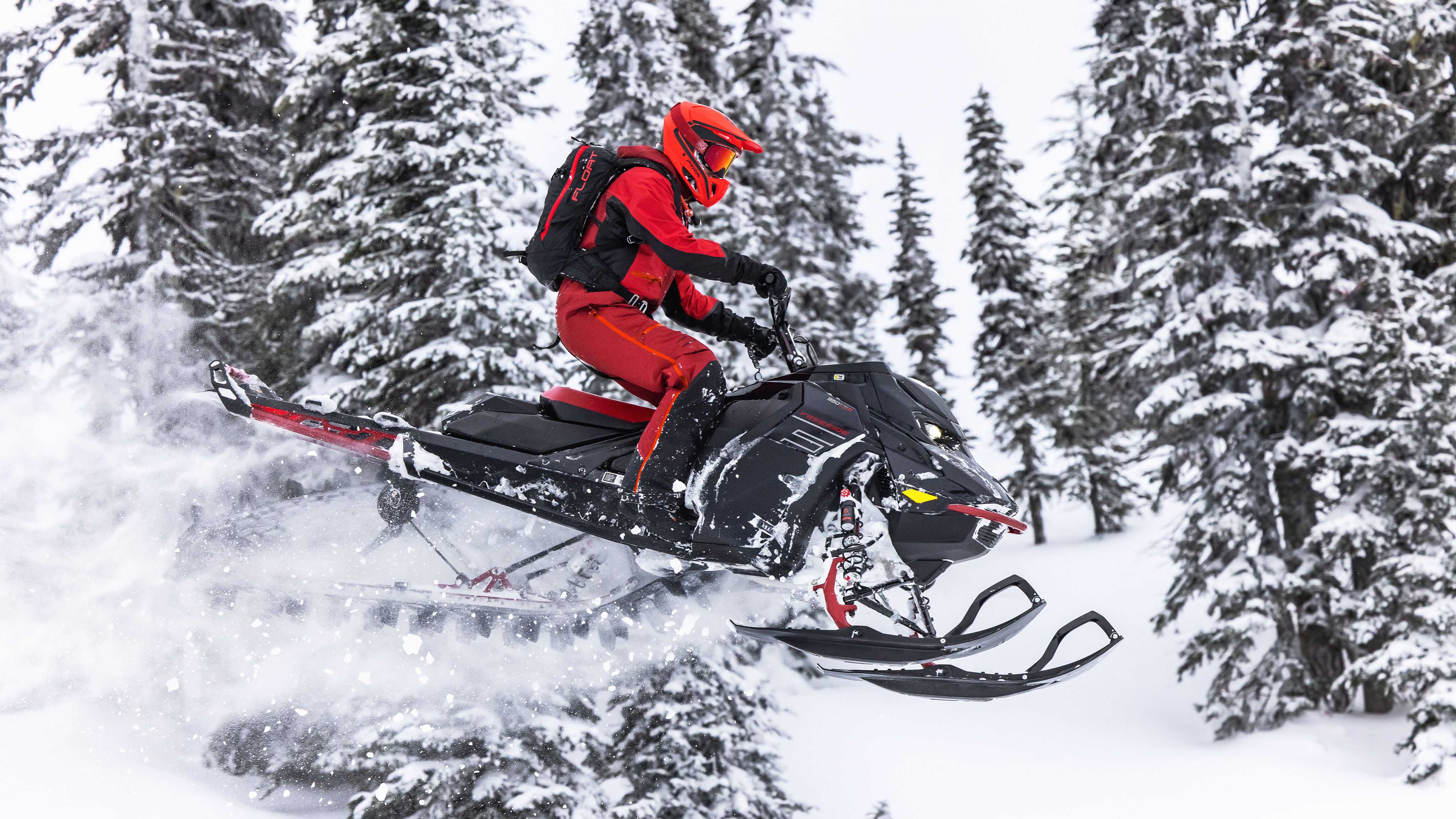 Возач кој скока во длабокиот снег со својата Ski-Doo моторна санка наменета за длабок снег.