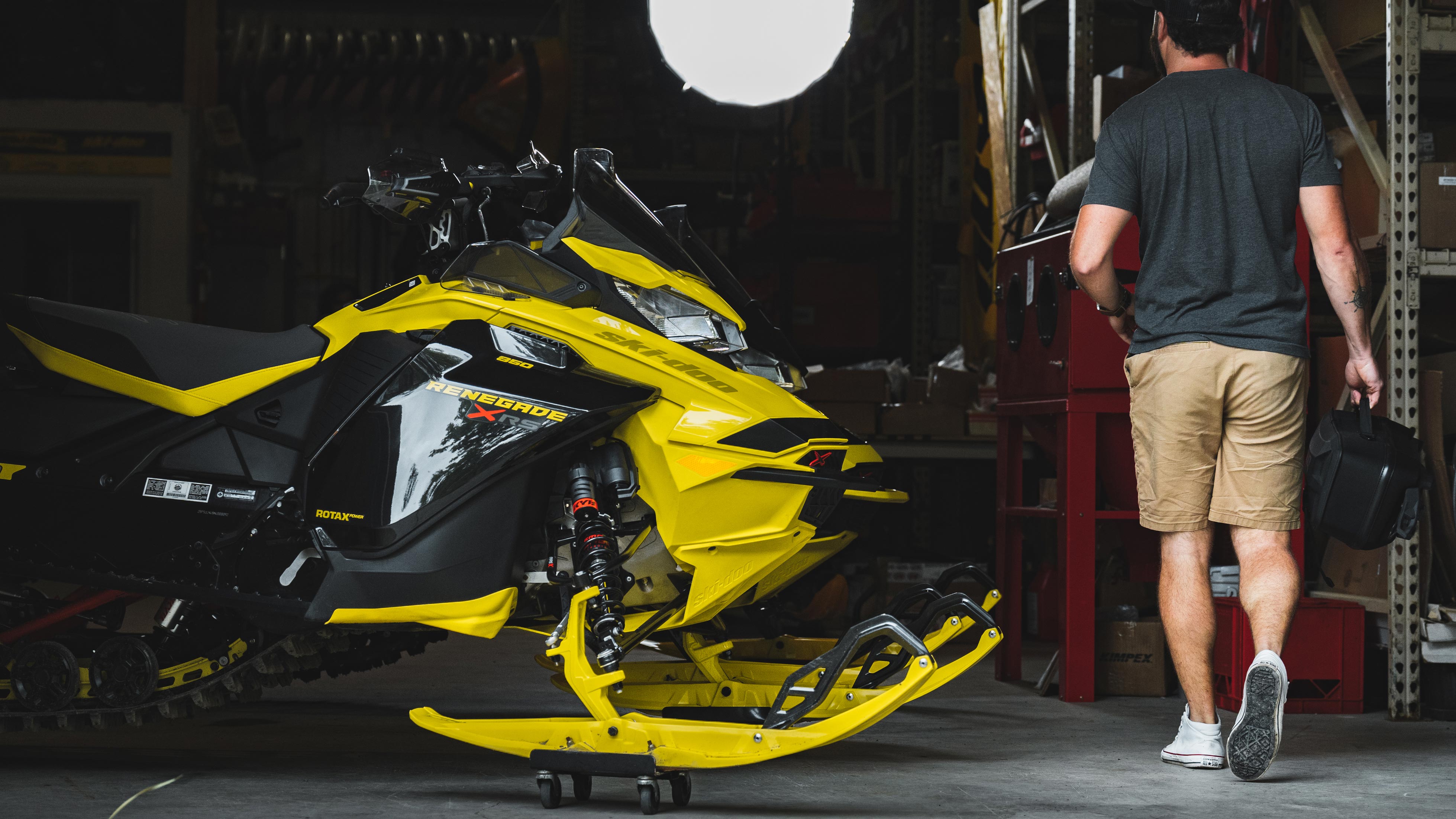 Corey Jinks next to his Ski-Doo snowmobile on his garage