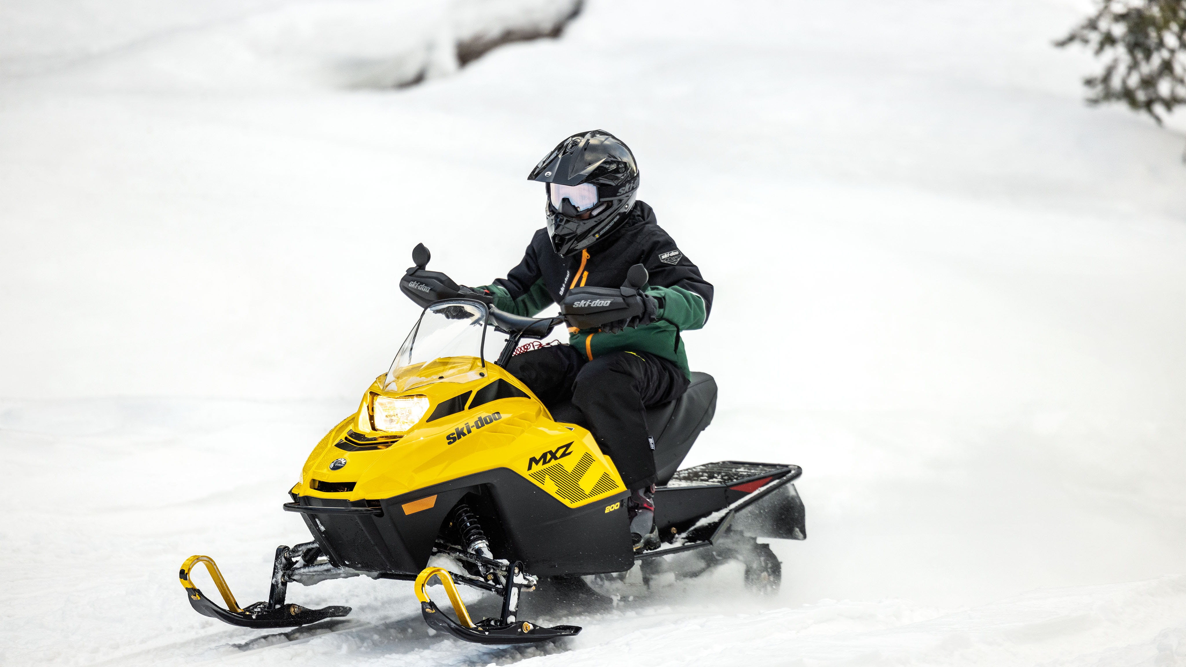 Mladý jazdec jazdiaci na Ski-Doo MXZ 200, snežnom skútri pre mladých