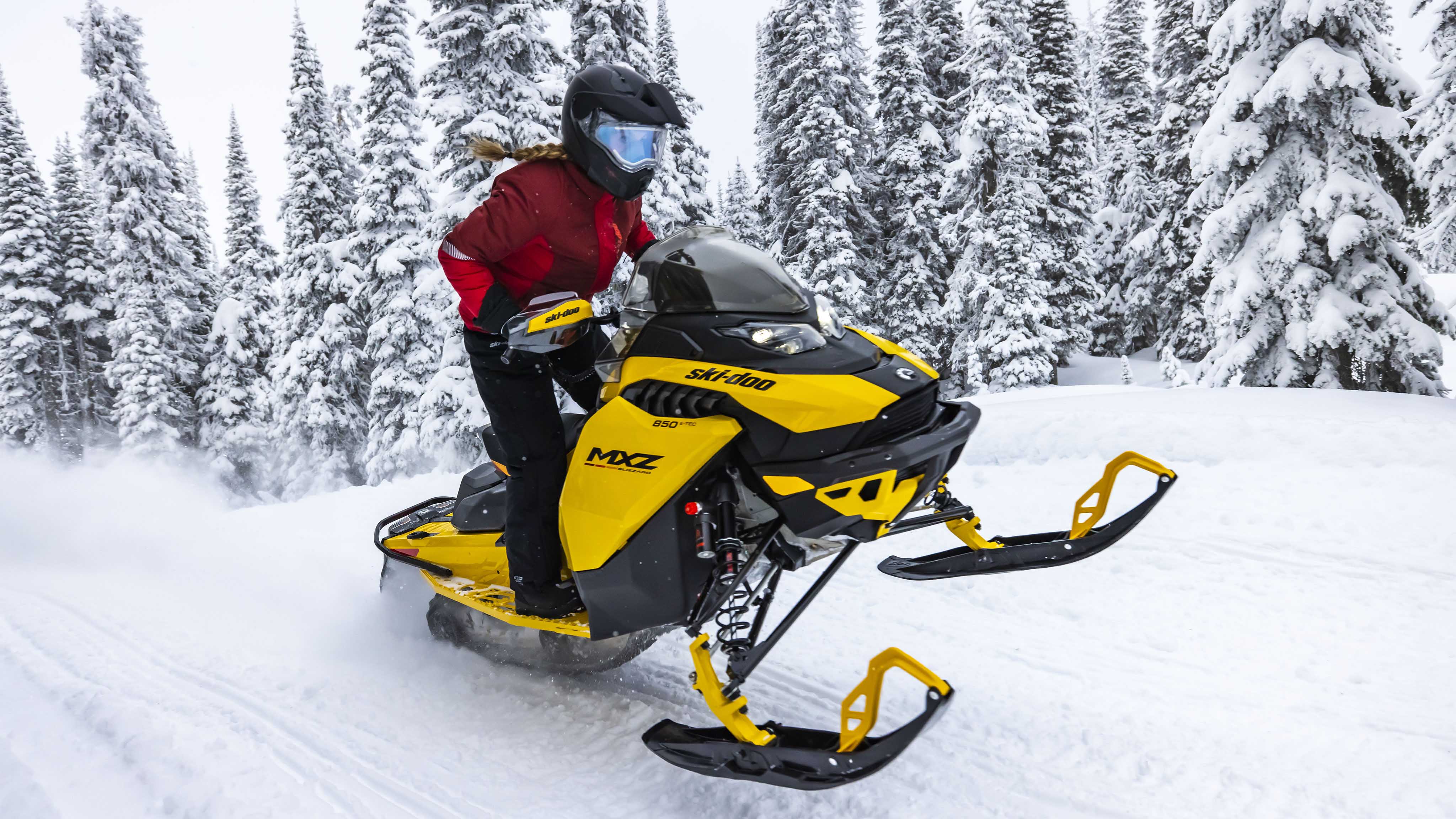 Žena stojí na snežnom skútri Ski-Doo MXZ model 2023
