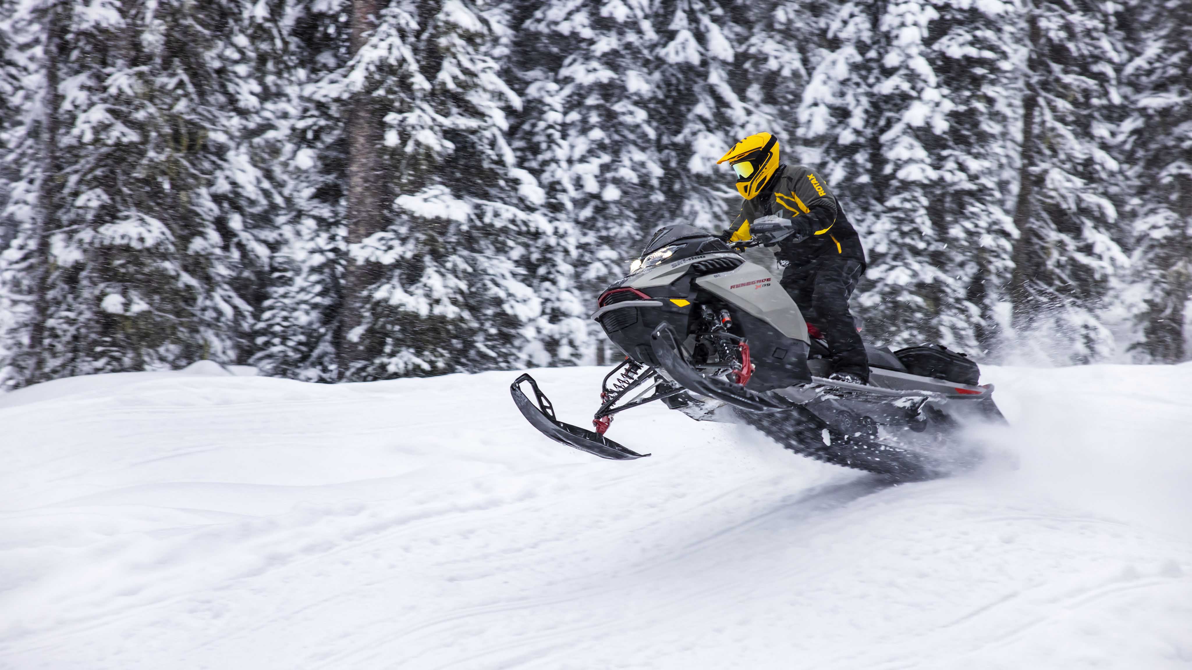 Возач кој ужива во брзината на својата Ski-Doo моторна санка долж паеката.