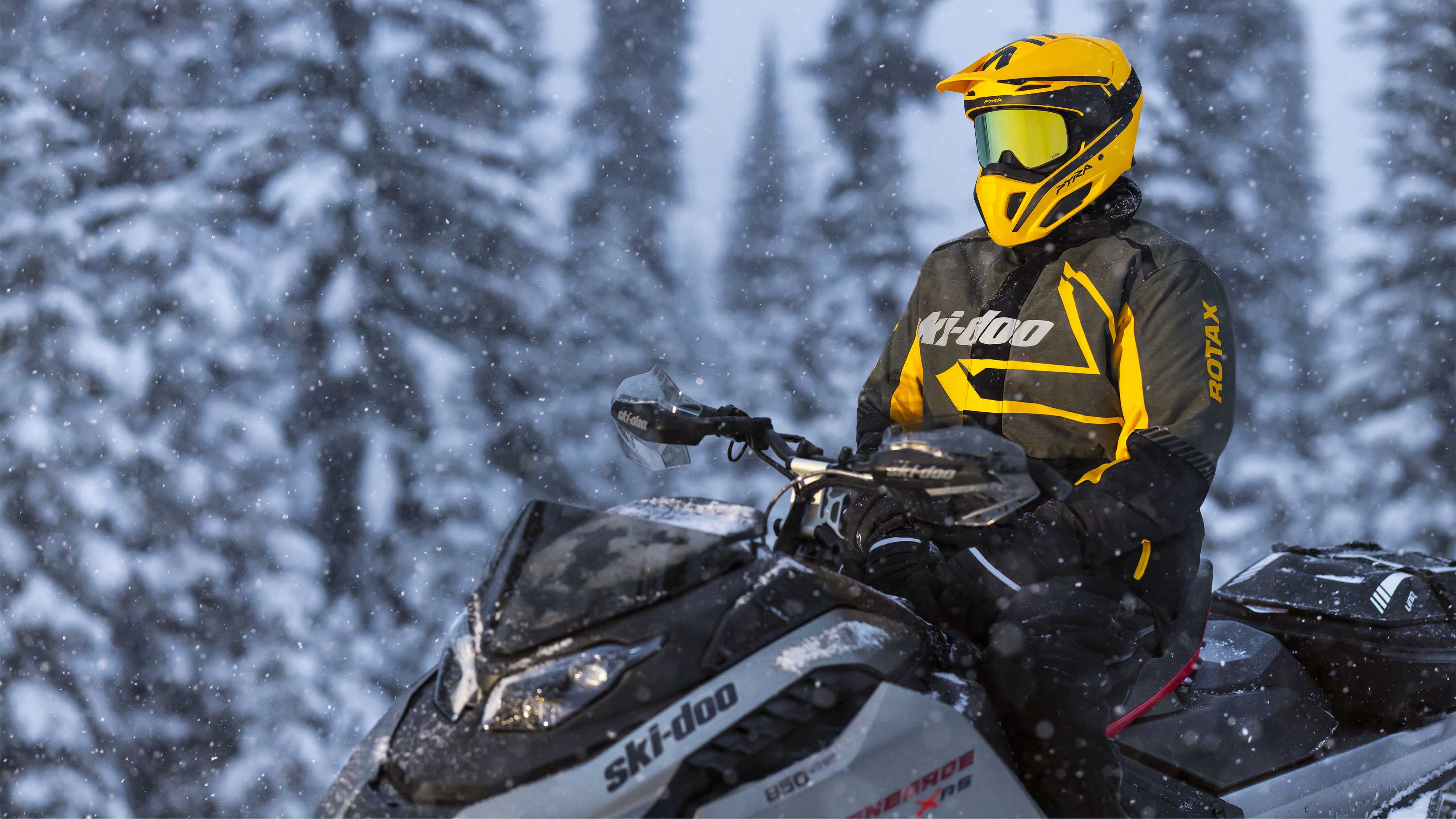 Man sitting on his snowmobile with the Pyra Helmet