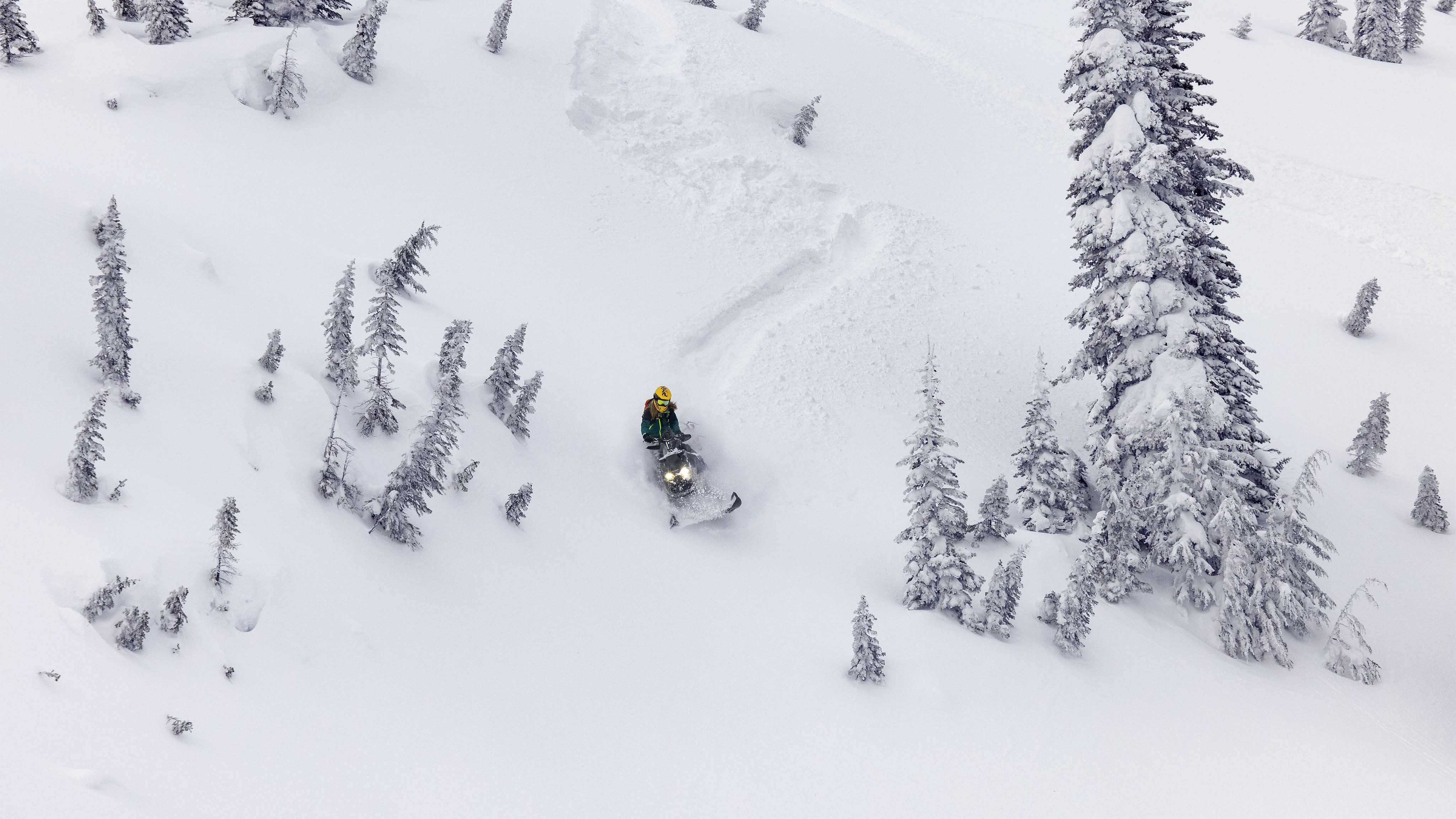 Muž jazdiaci v horách so skútrom Ski-Doo Summit model 2023